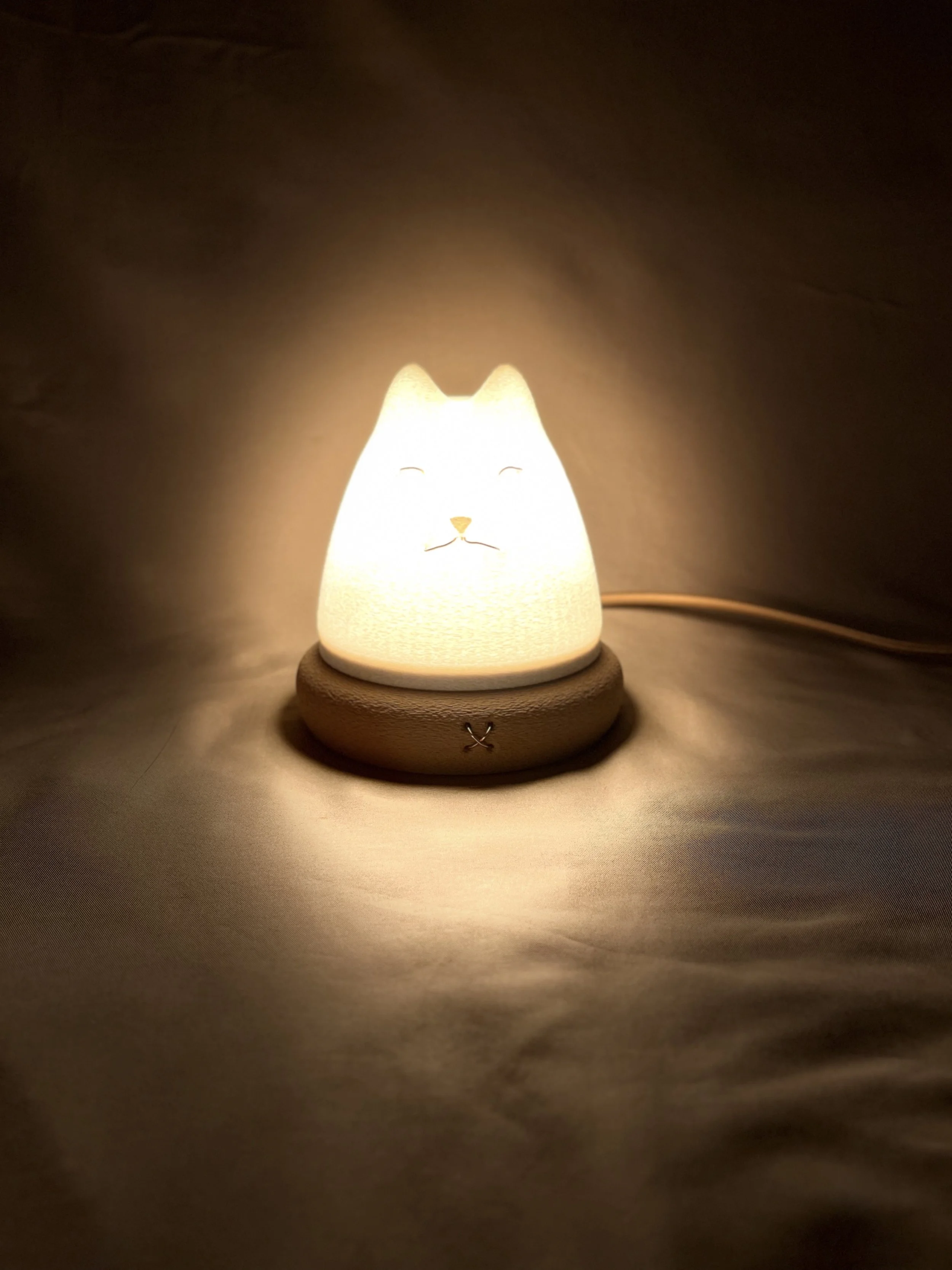 Cute cat-shaped nightlight glowing softly in a dark room.