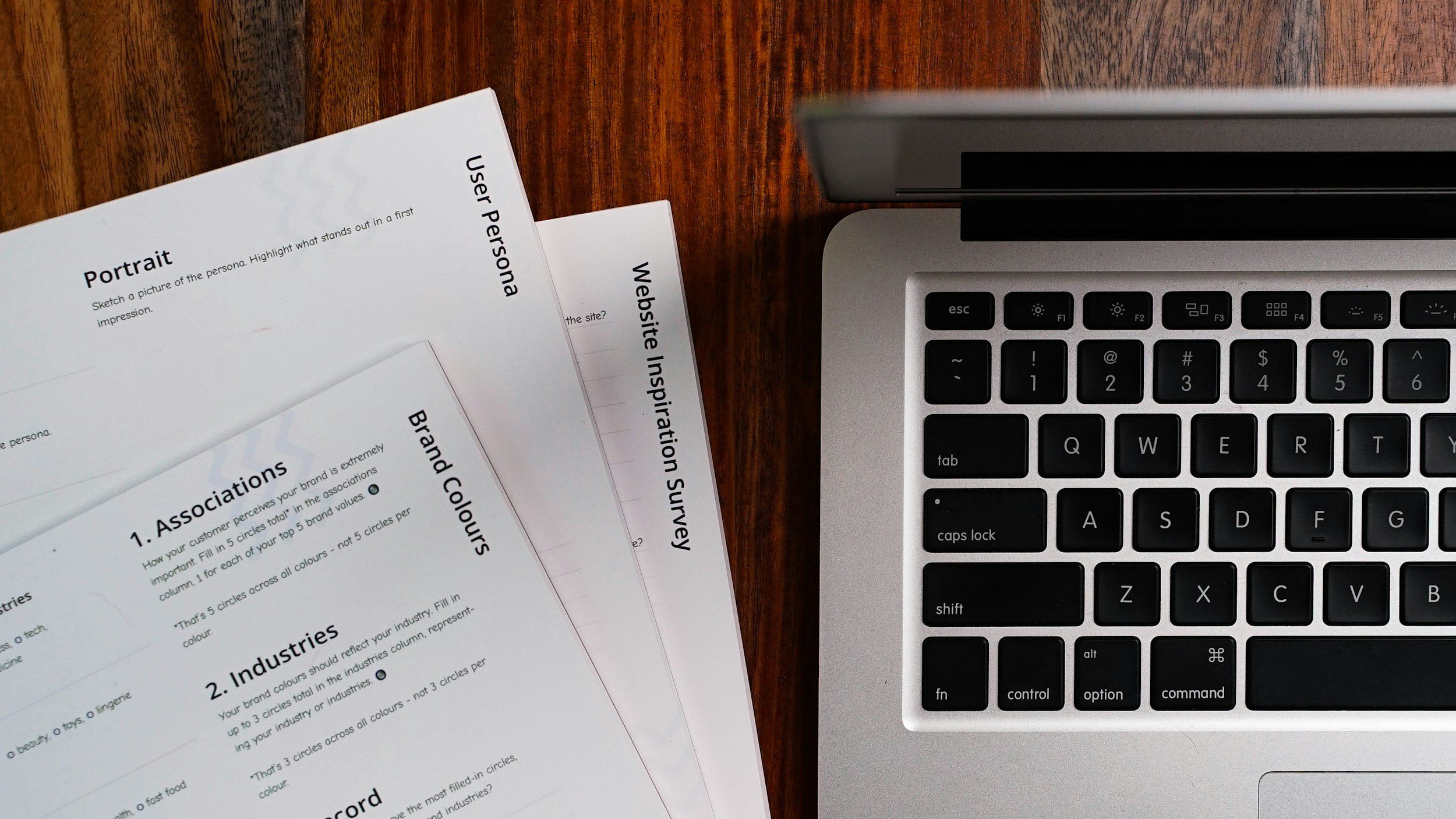 A bird's-eye view of a laptop keyboard next to sheets of printed paper to convey website copywriting