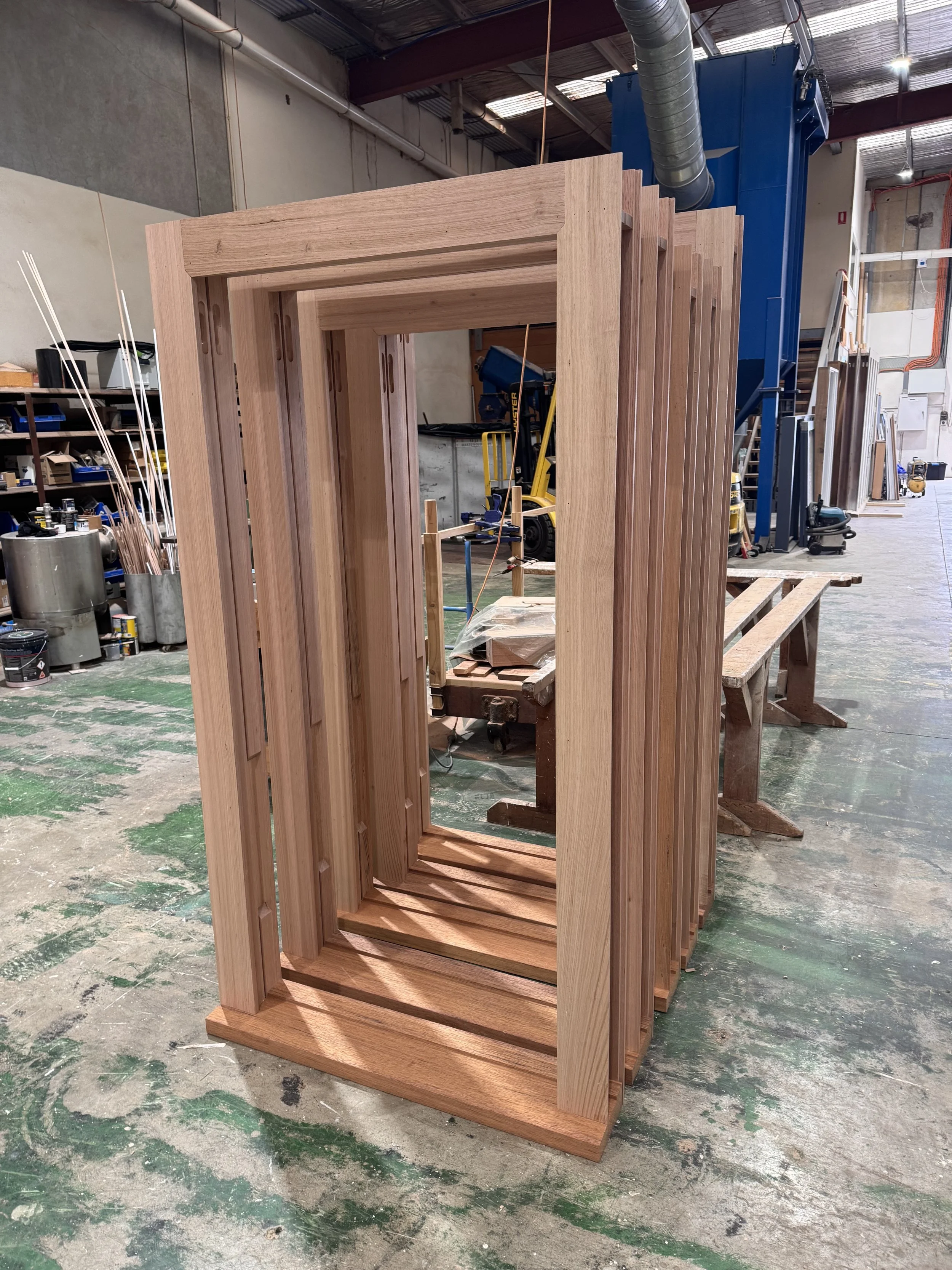 Stacked wooden door frames in a woodworking shop.