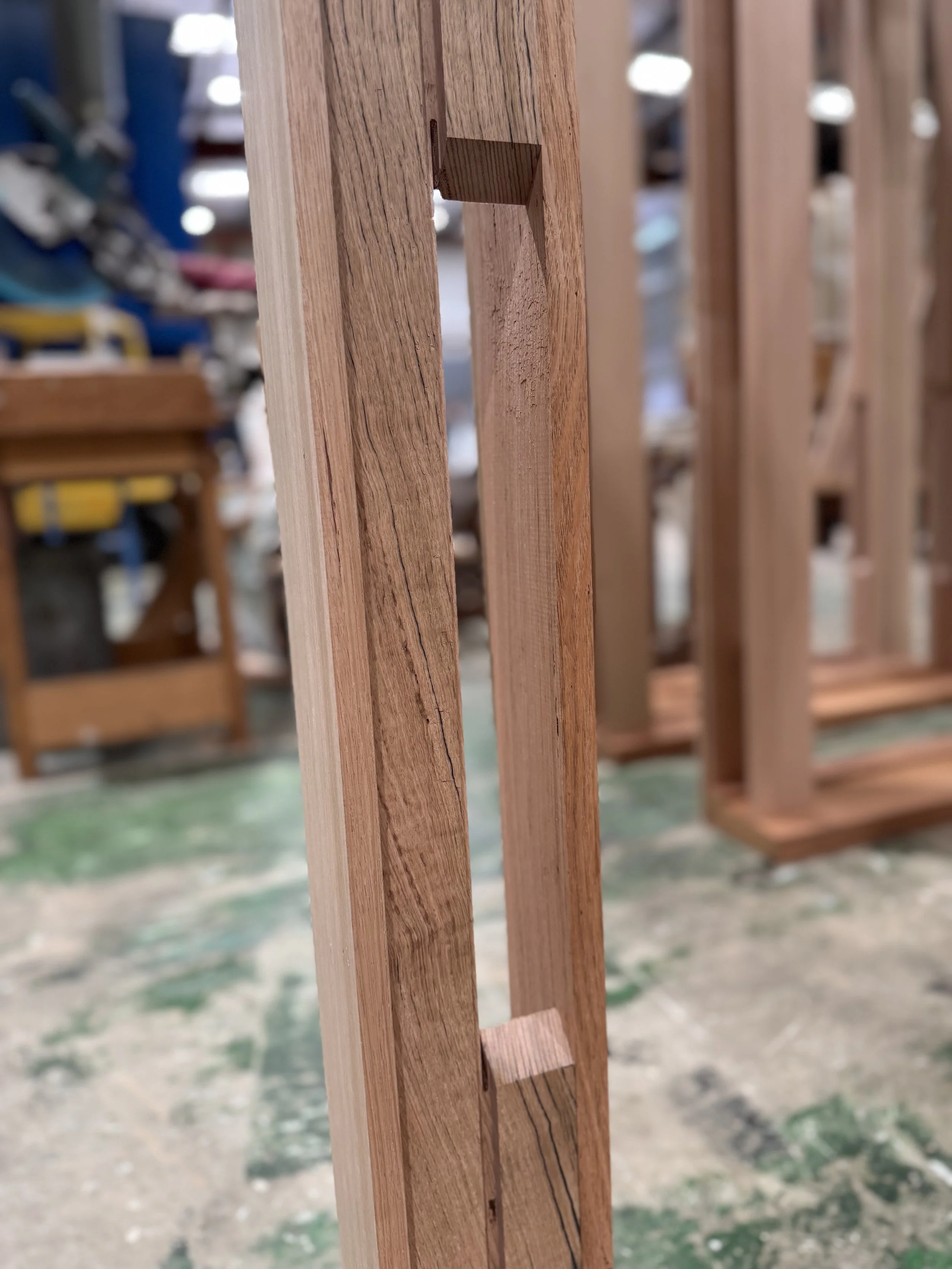 Close-up of a wooden frame with a slot and notch, likely part of furniture construction, in a workshop.