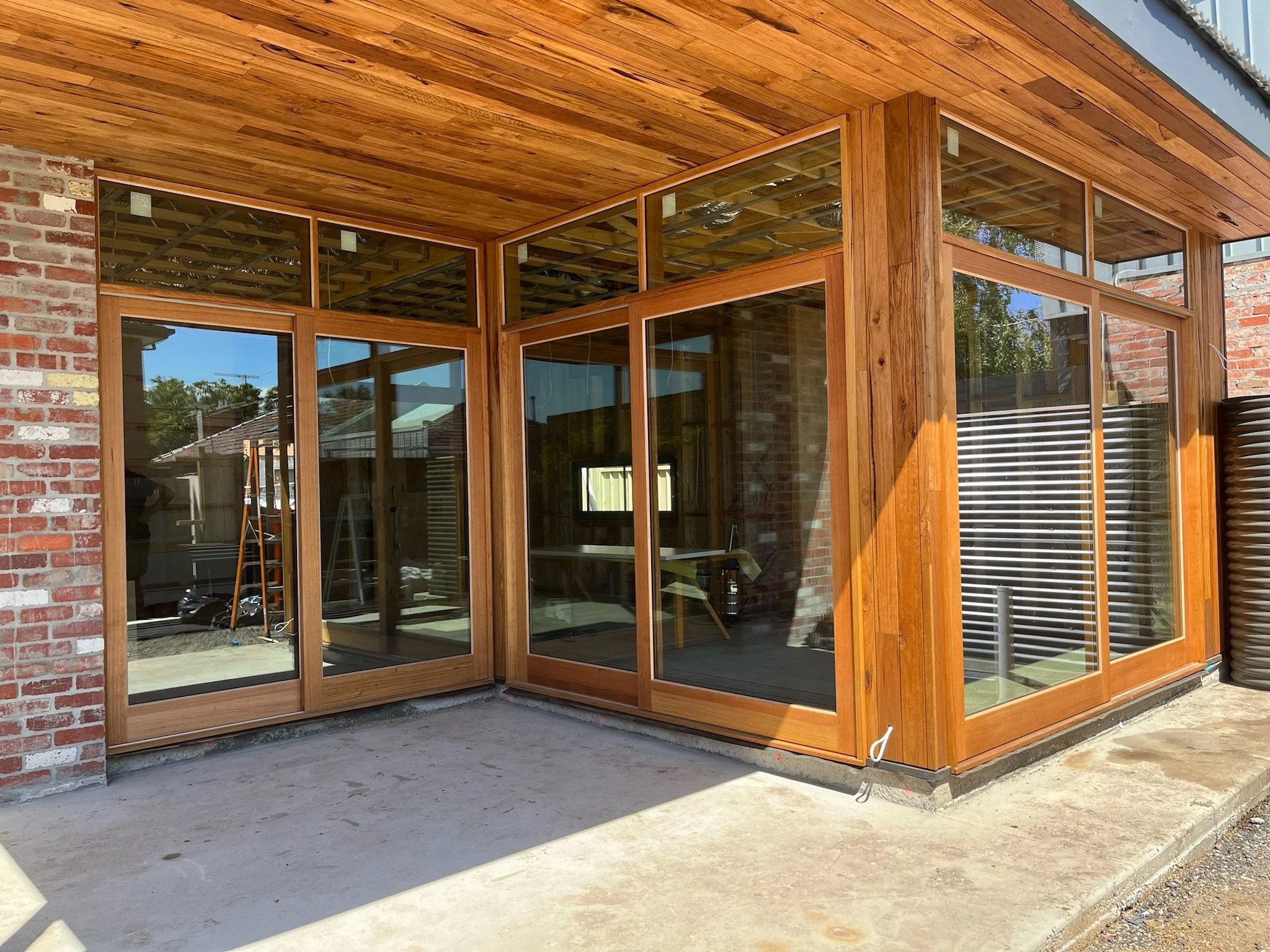 New construction with large glass windows and wooden framing, exterior view of a house.