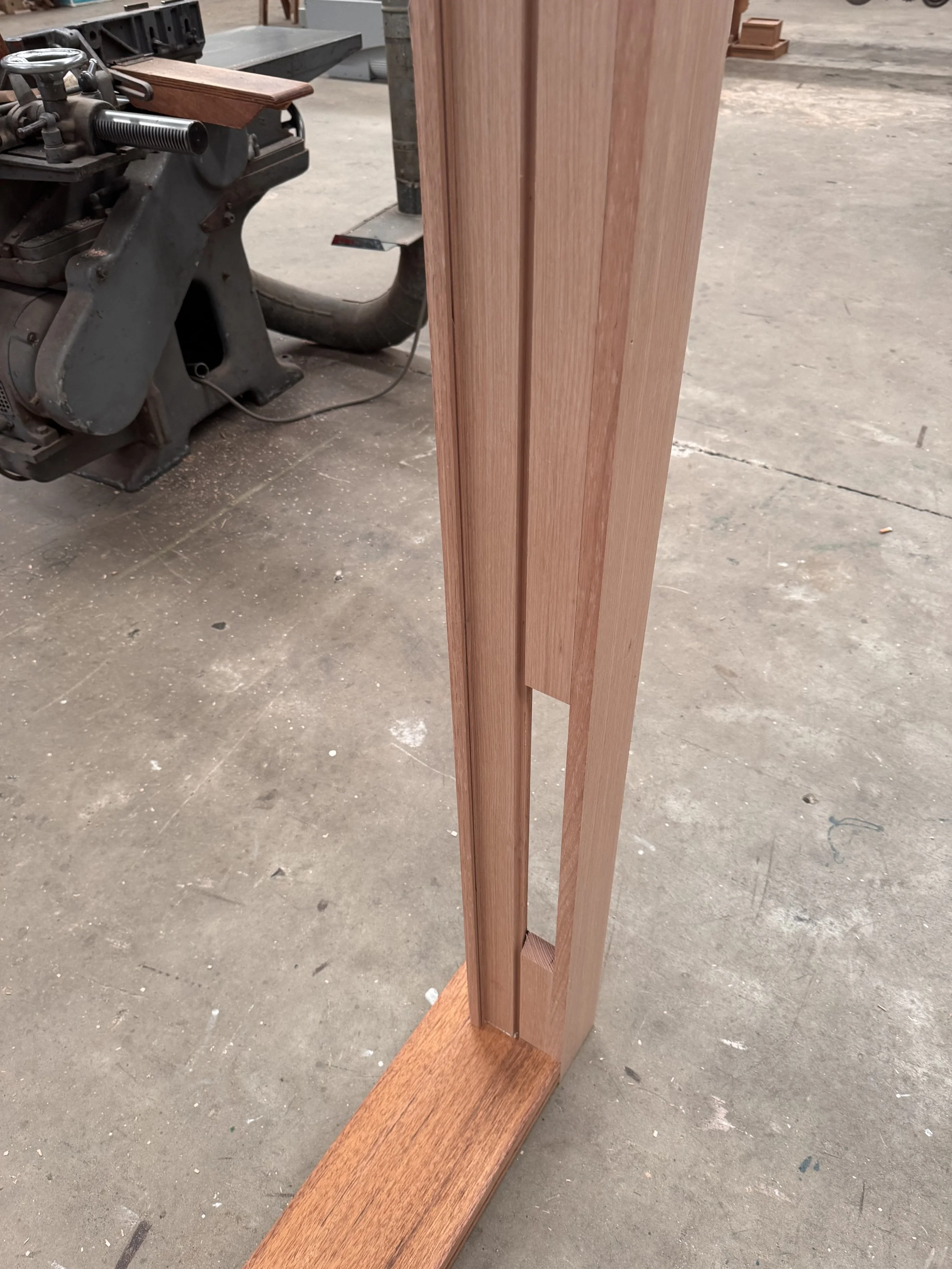 Close-up of a wooden piece with vertical grooves, part of a furniture or cabinetry project in a workshop.