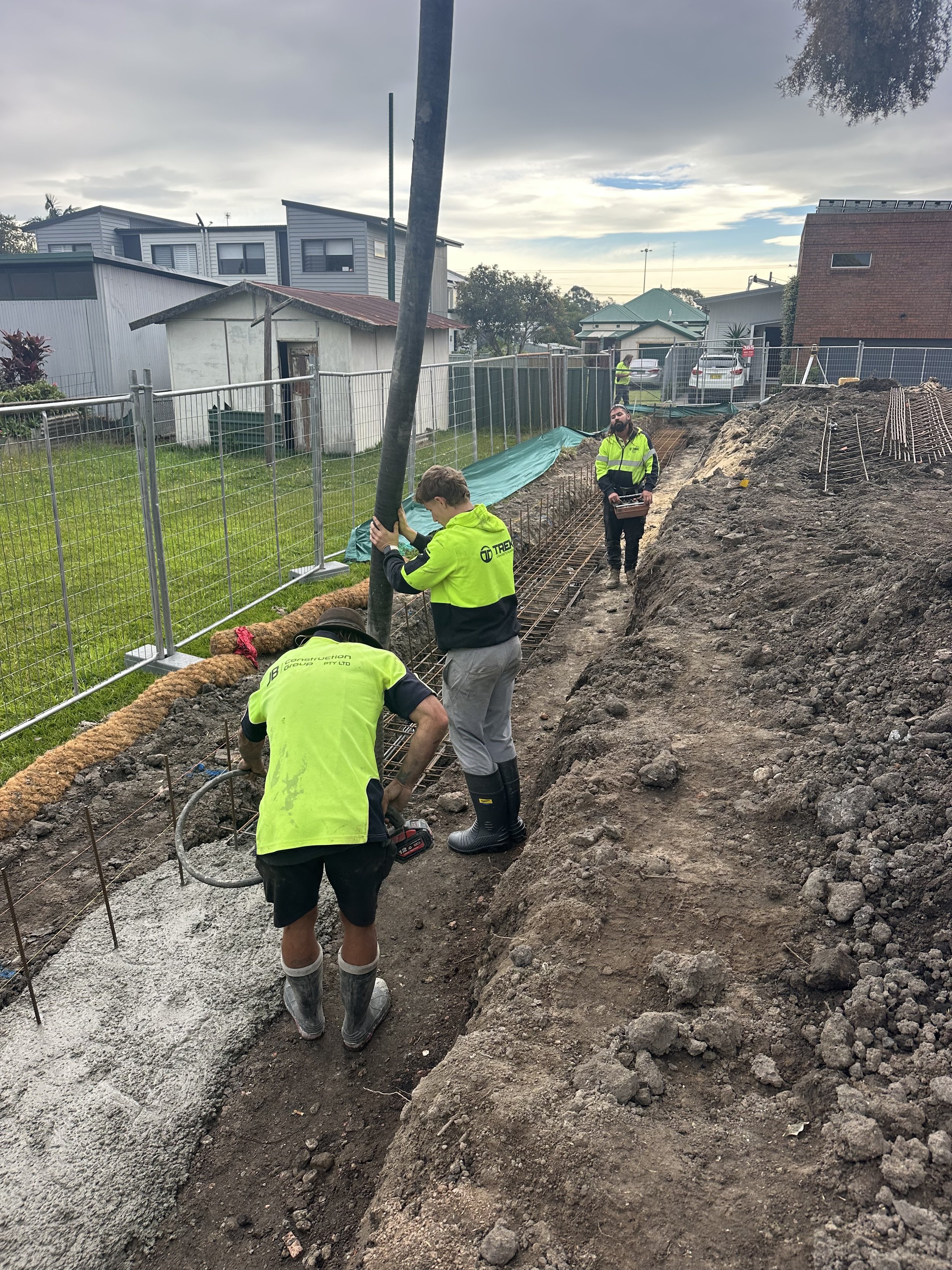 Construction workers in high visibility clothing pouring and leveling concrete for a foundation or walkway at a construction site outdoor