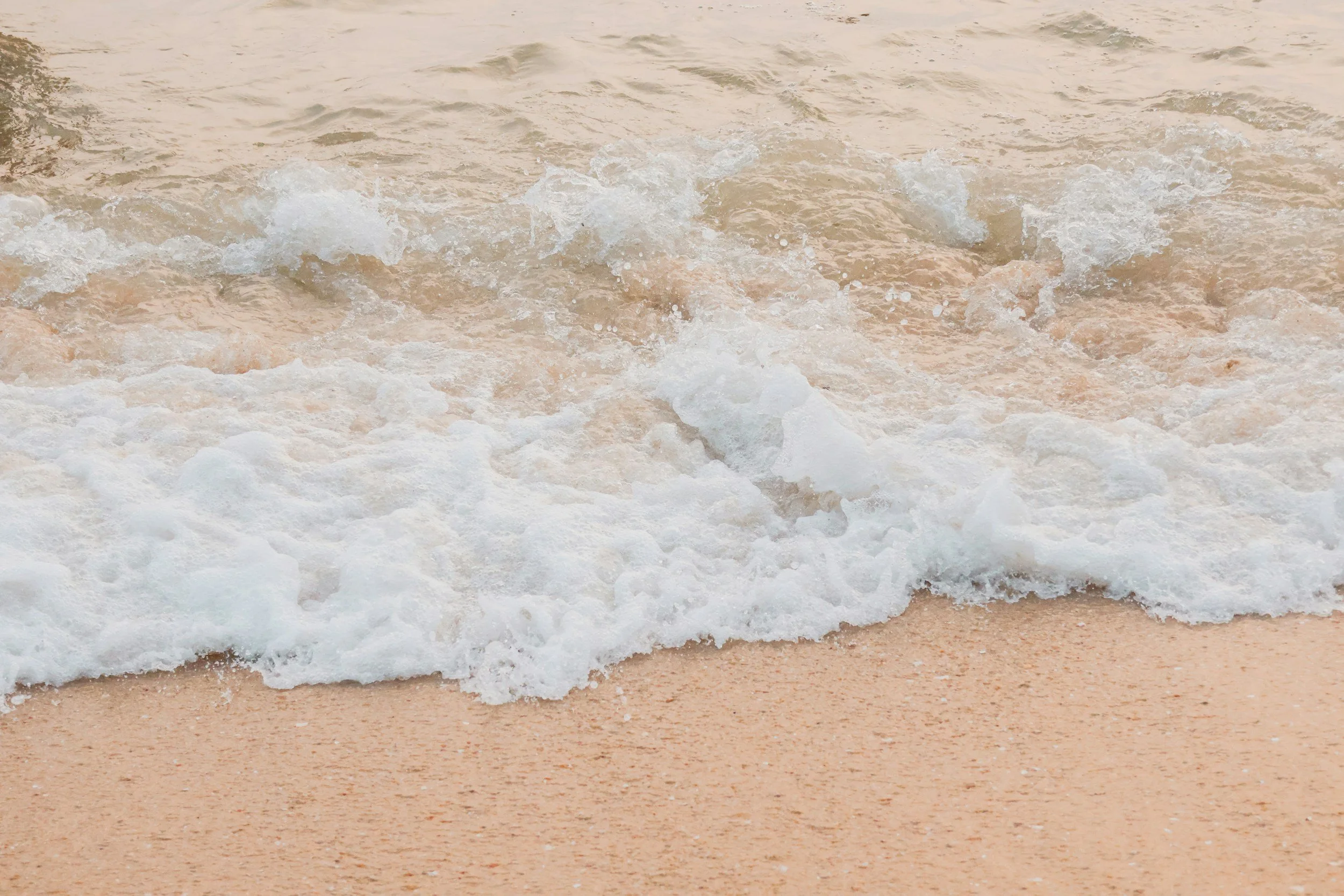 Sonya Lee, executive mentor and author of Channels of Light. Waves crashing onto a sandy shoreline.
