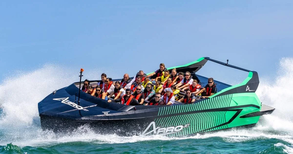 A boat with many passengers riding on the water during sunny weather.