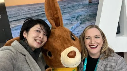 Two women smiling with a large bunny mascot at an indoor event