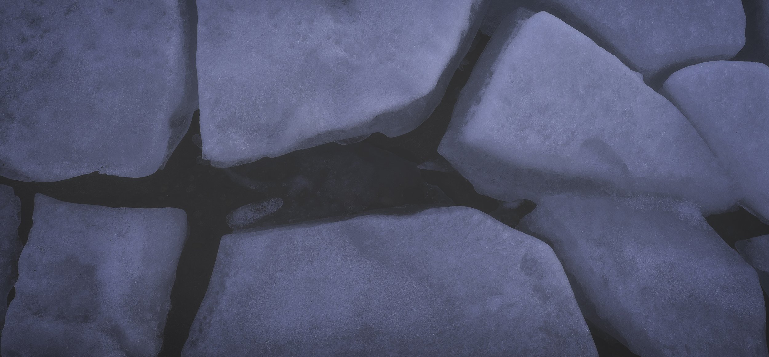 Close-up of snow-covered stones with dark gaps in between.