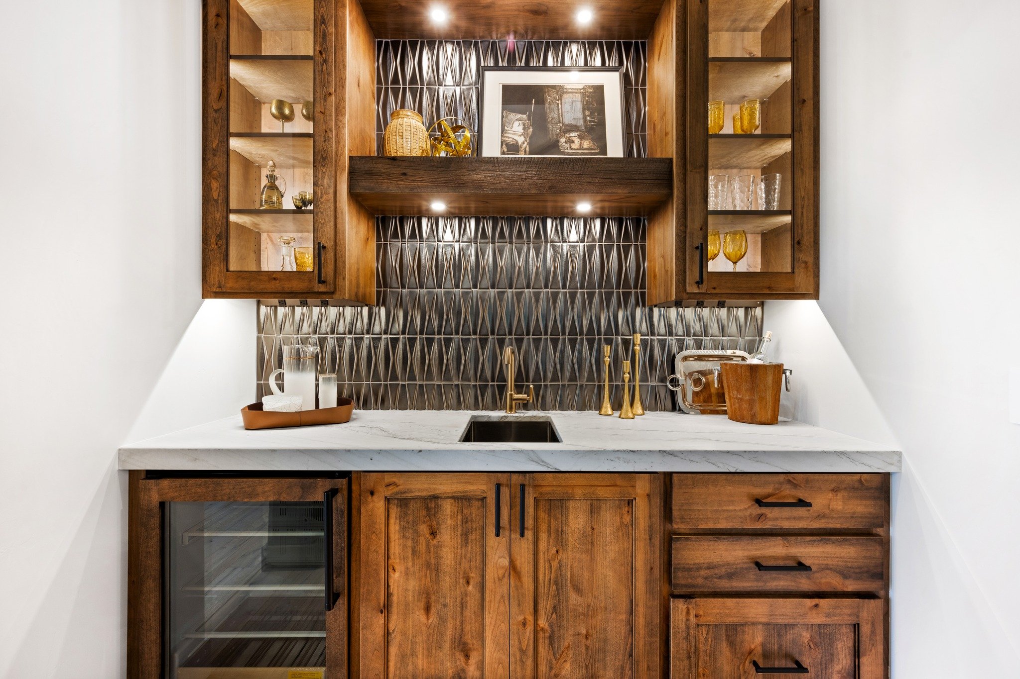This custom bar area brings together rich wood tones, striking tile, warm lighting, and clean finishes to create a space that feels both elevated and inviting. Built for entertaining and designed to stand out, it is one of those features that instant