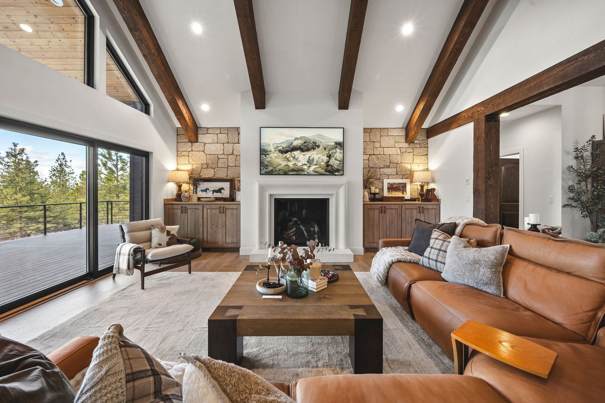 This living space was designed to bring the outdoors in, with soaring ceilings, natural wood beams, and expansive windows that frame the beauty of North Idaho. From the custom stone fireplace to the warm textures throughout the room, every detail is 