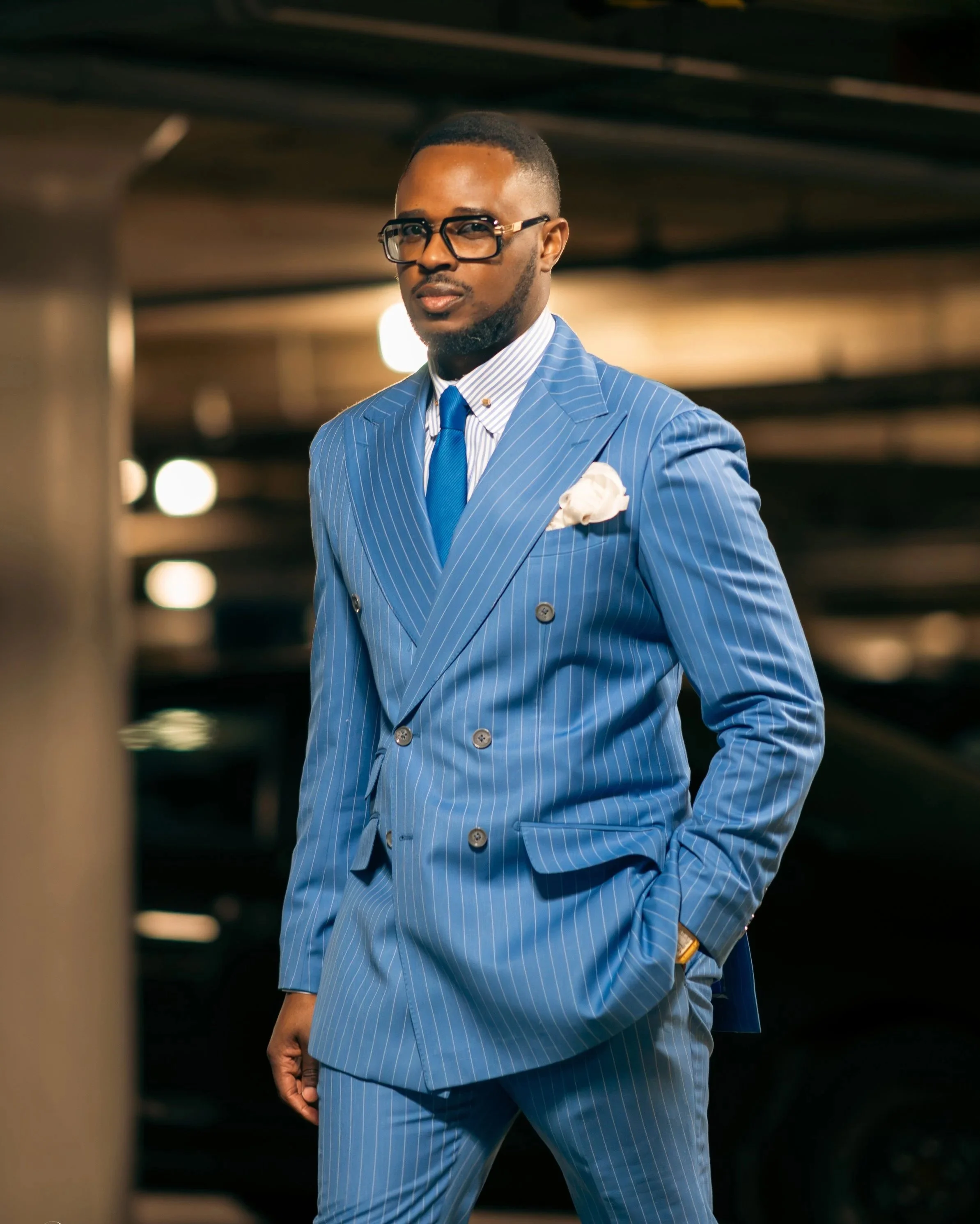Raffiné Couture model standing and looking at the camera with hands in his pocket wearing RC Blue Pinstripe Double-Breasted Suit