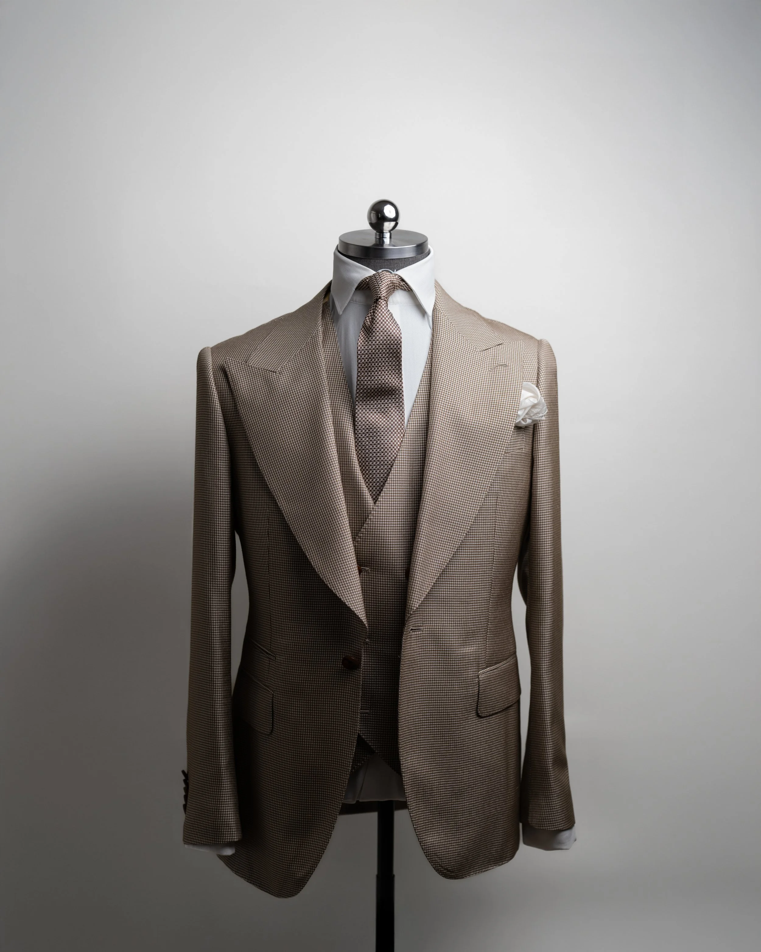 RC Brown Houndstooth Three-Piece Suit on a standing mannequin, paired a white shirt and a houndstooth tie