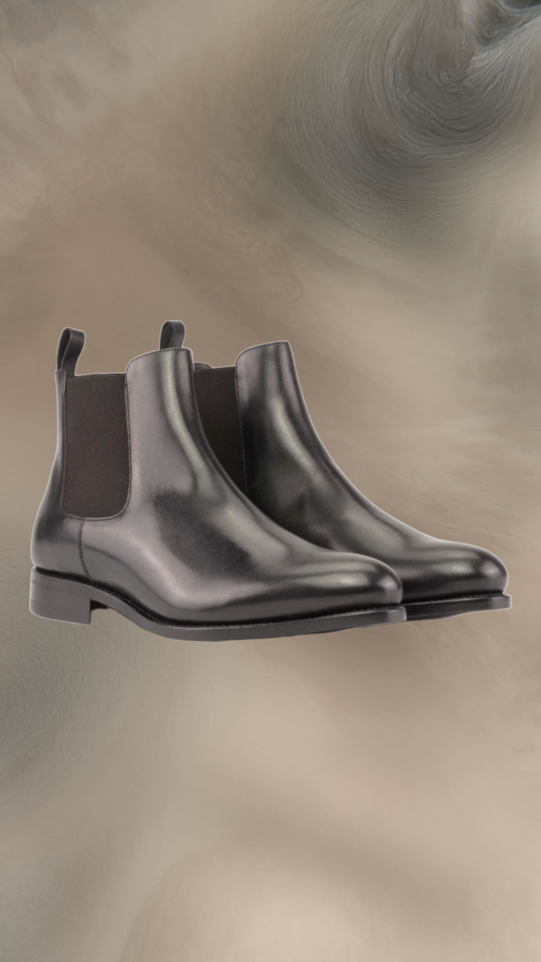 A pair of black leather Chelsea boots with elastic side panels, set against a blurred, swirling background.
