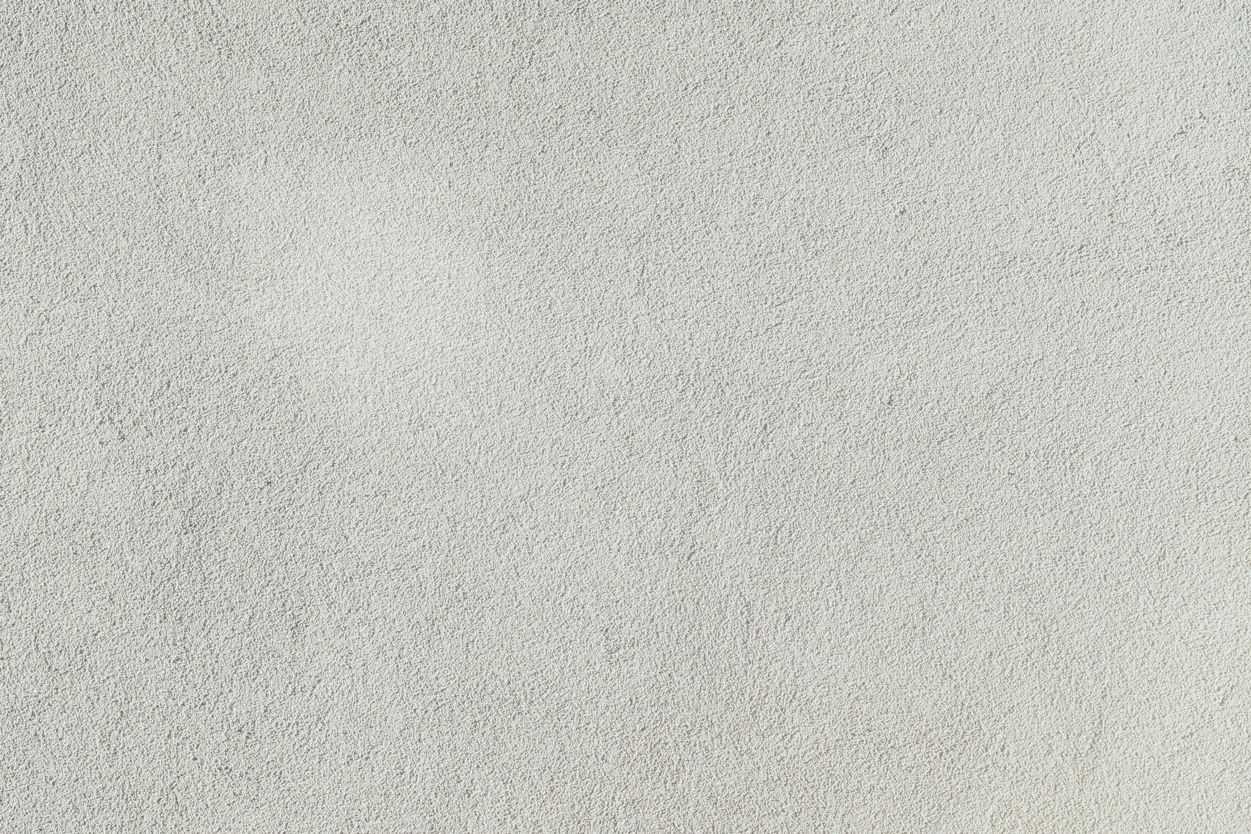A textured beige wall with a rough, sandy surface.
