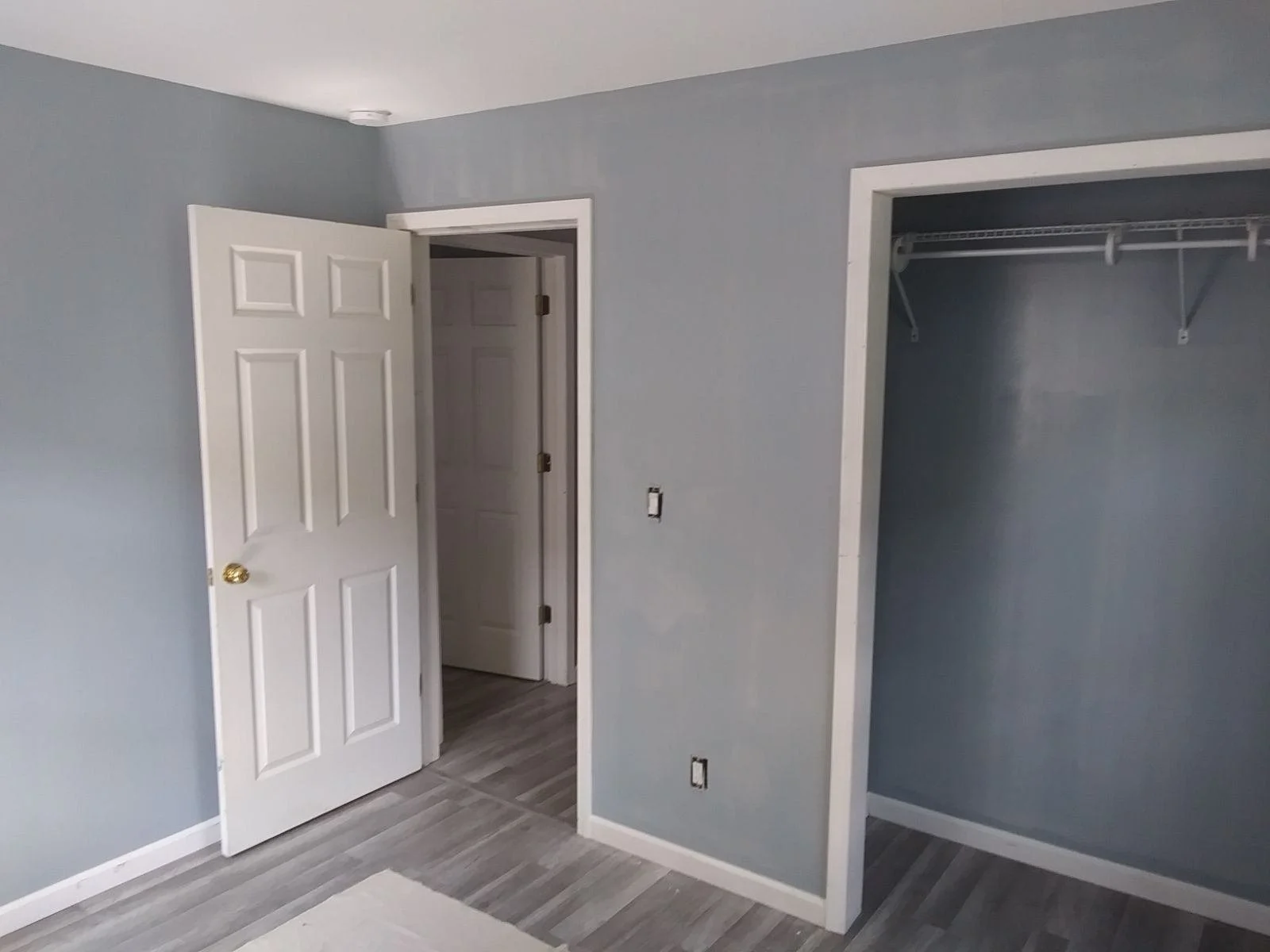 Empty room with grey walls, open closet, and white door