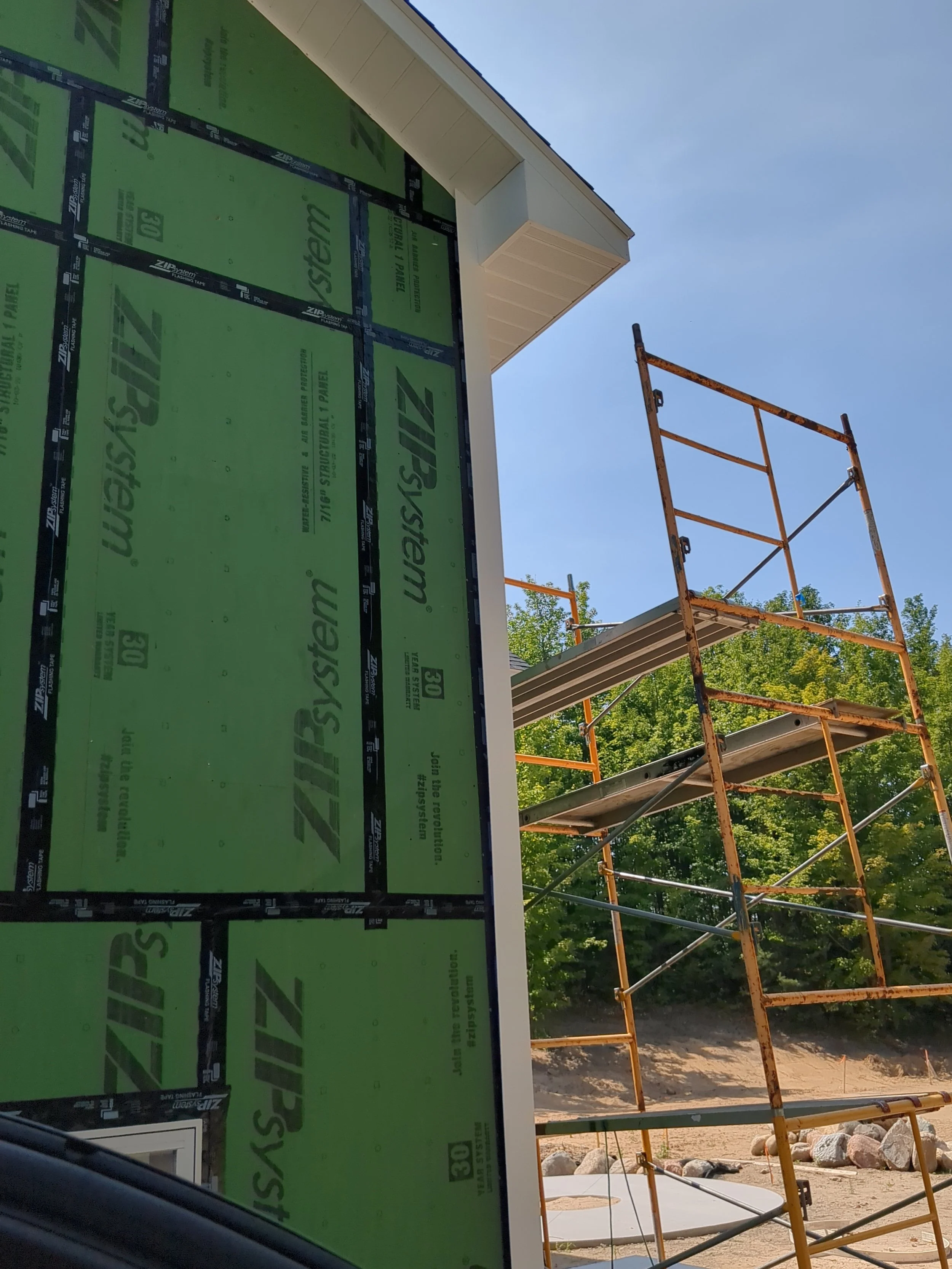Building under construction with ZIP System sheathing and scaffolding outdoors.