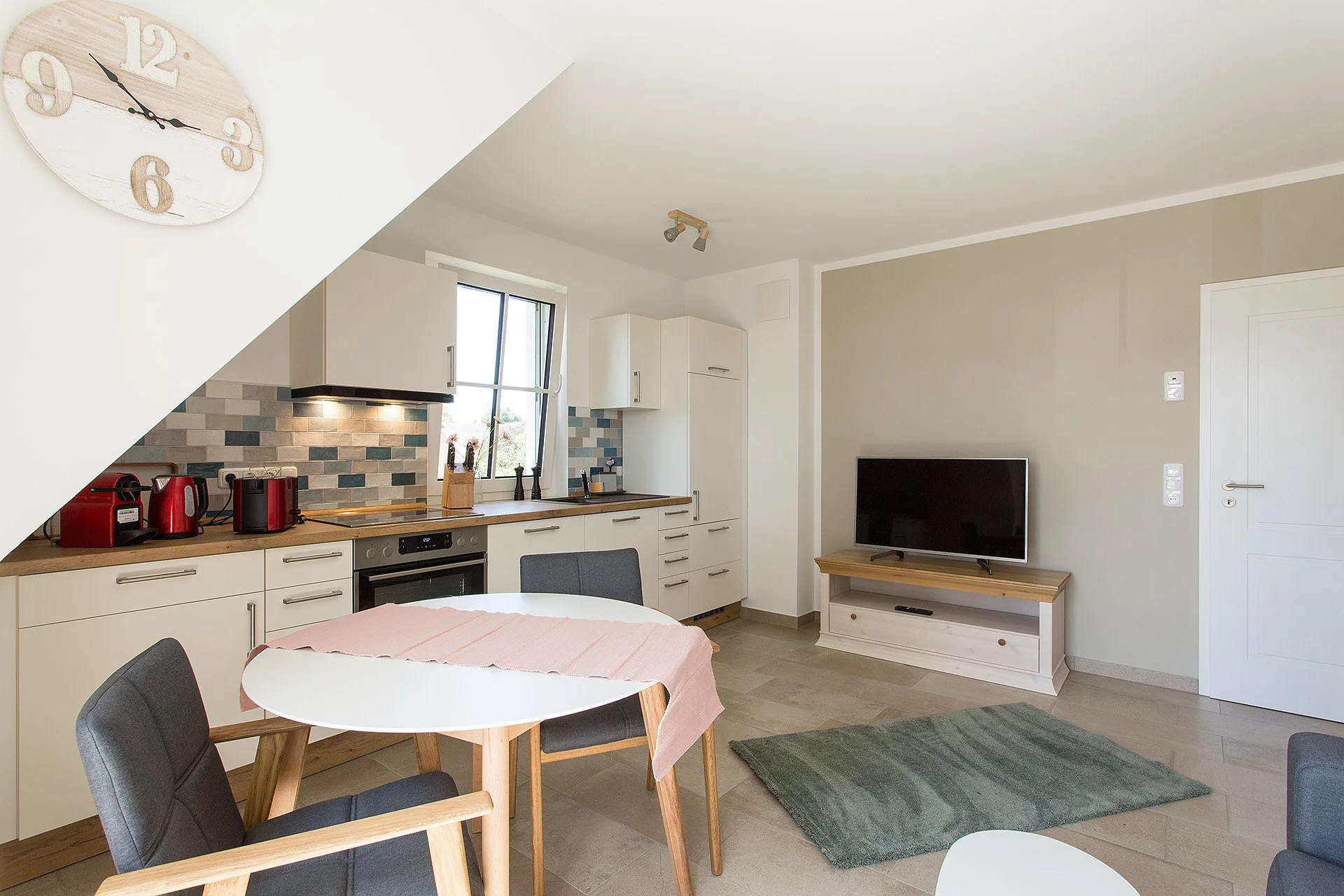 Moderner Wohnungsküchen- und Wohnzimmerbereich mit Esstisch, Küchenzeile, TV und zeitgemäßem Dekor.