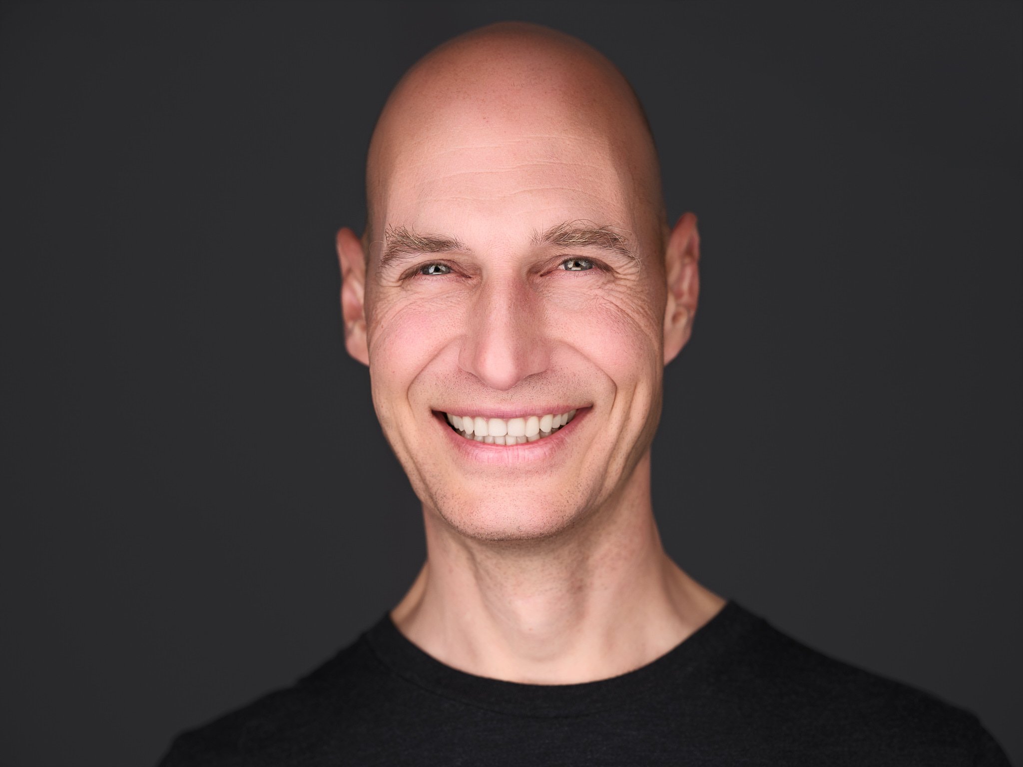 Lächelnder Mann mit Glatze im schwarzenn T-Shirt