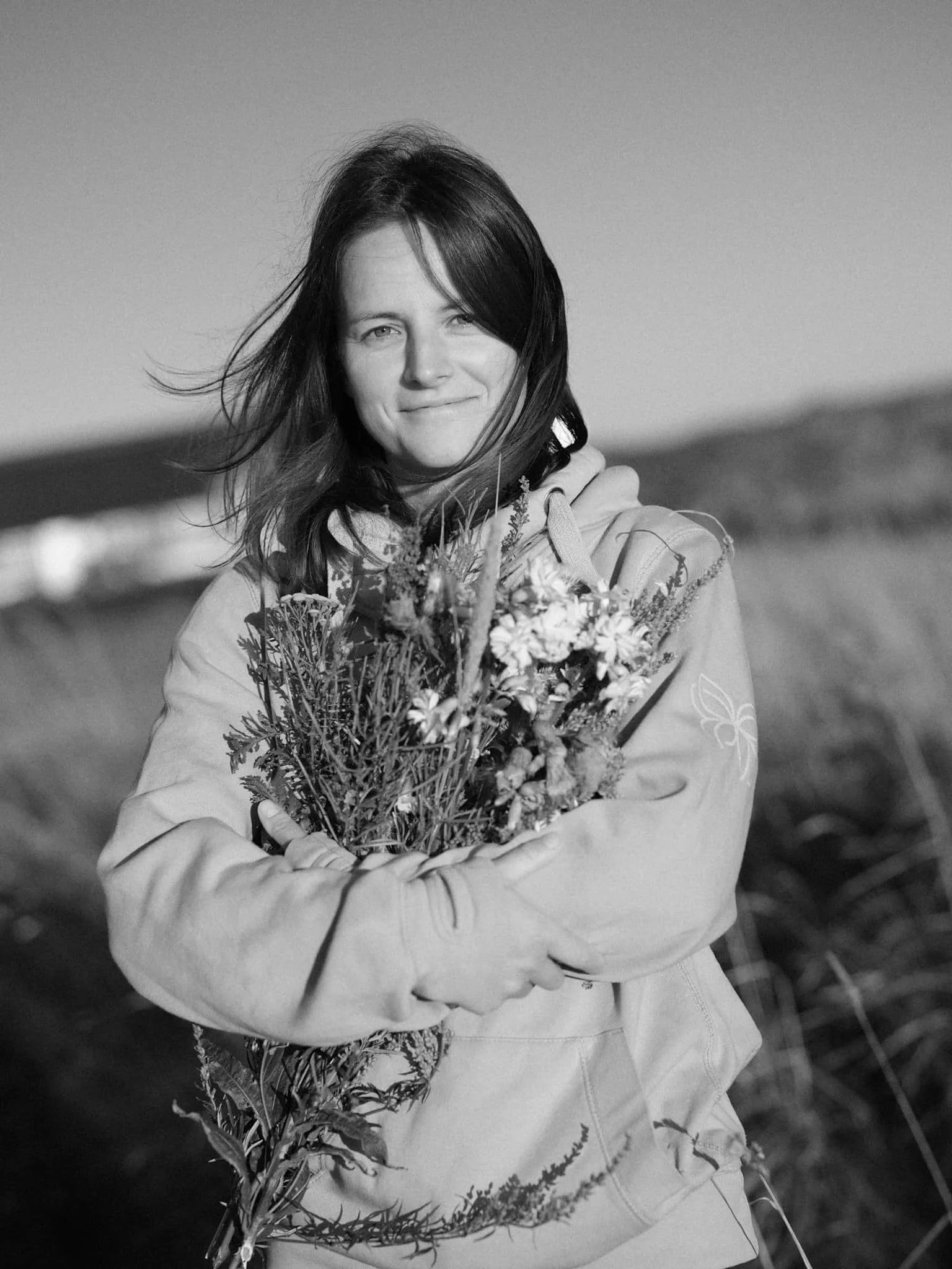 Junge Frau mit Wildblumen in Dünenlandschaft s/w