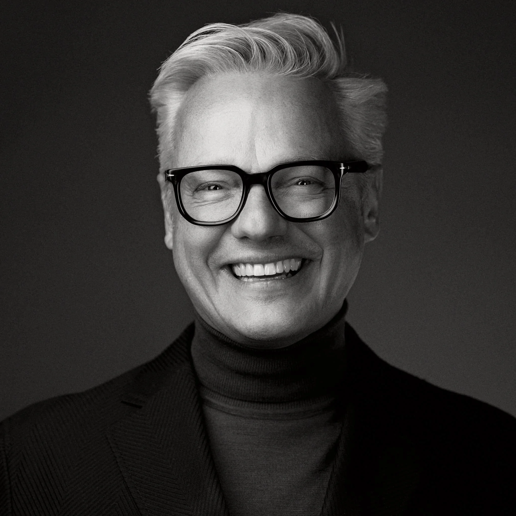 Lachender Mann mit Brille und grauen Haaren s/w