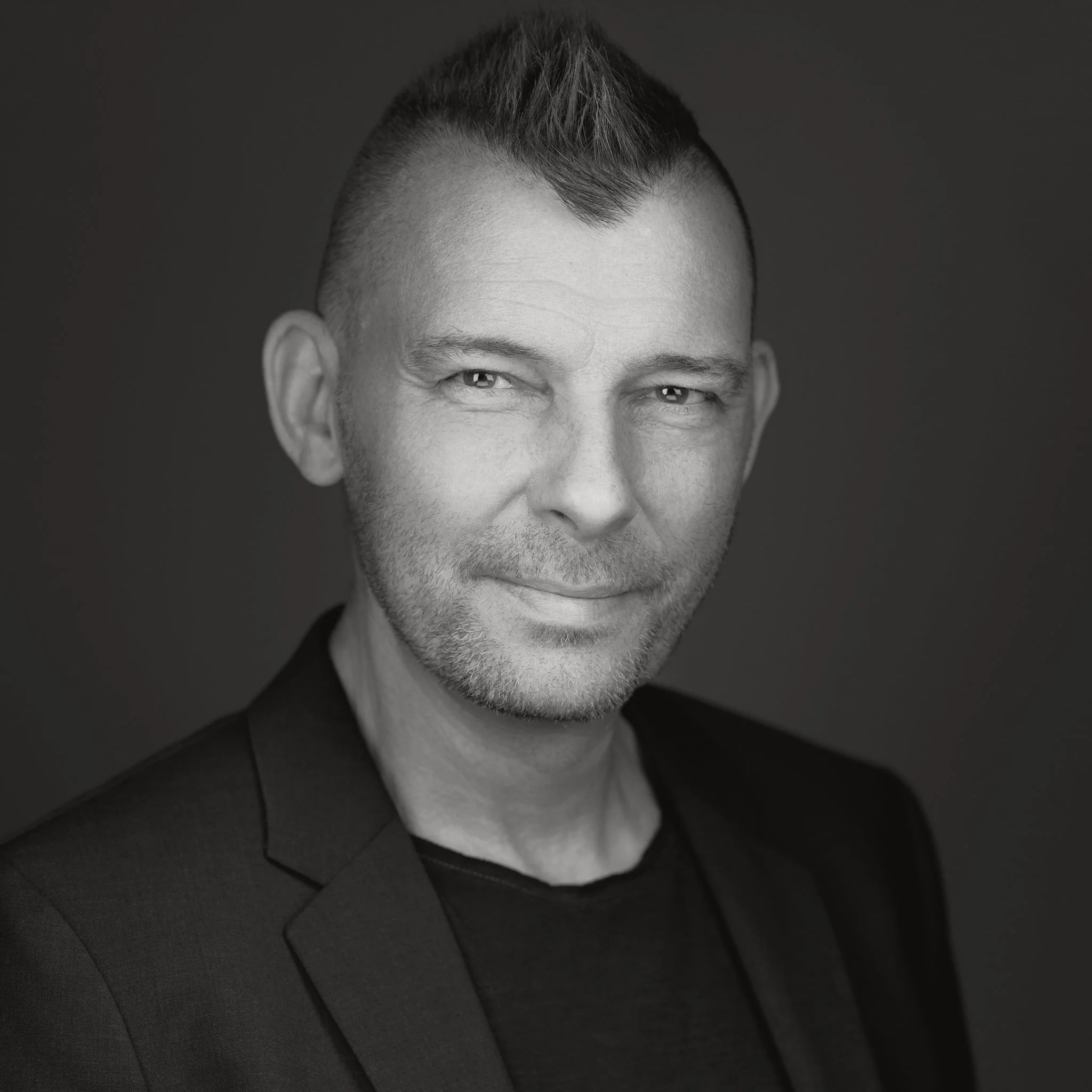 Mann mit irokesen Haarschnitt im Sakko s/w