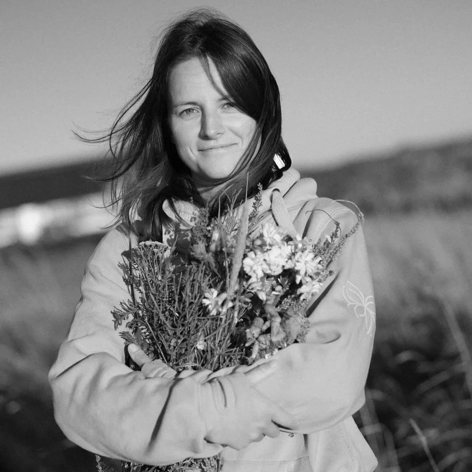 Junge Frau mit Wildblumen in Dünenlandschaft s/w