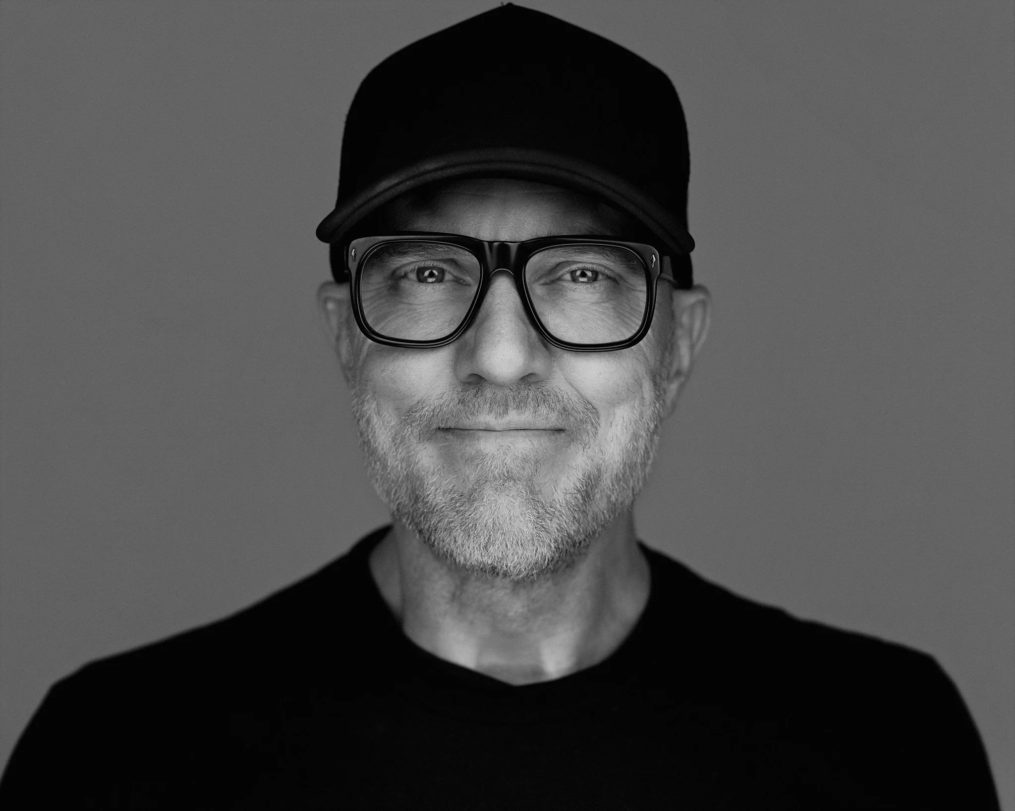 Freundlich lächelnder Mann mit Brille und Basecap in s/w