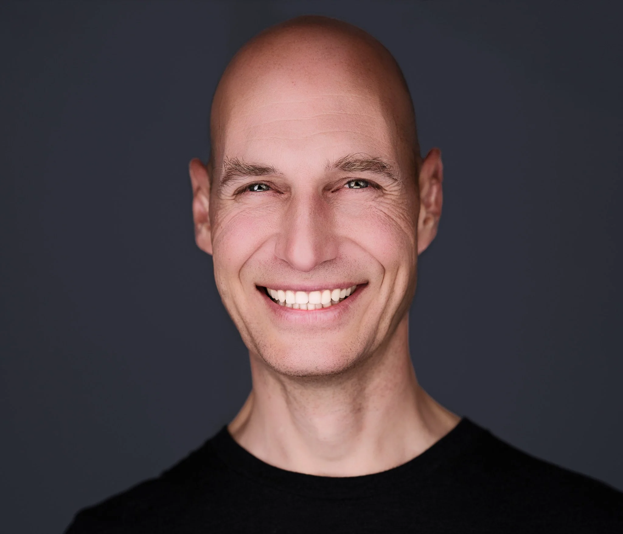 Lächelnder Mann mit Glatze im schwarzenn T-Shirt