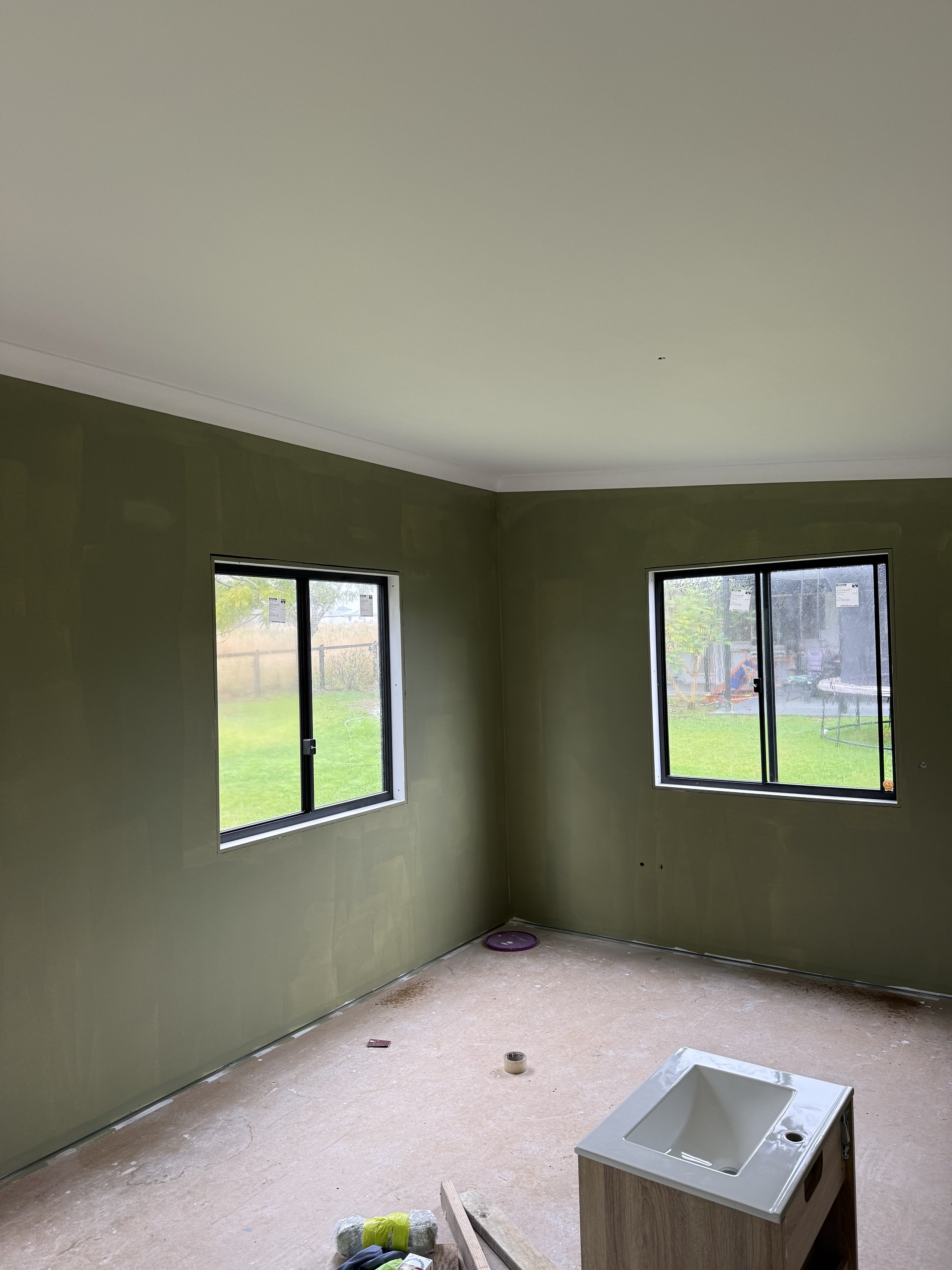 Final interior painting of tiny home with olive green walls and bright white ceilings.