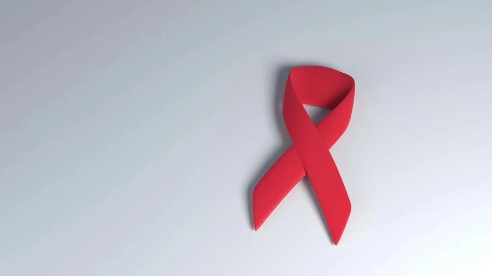 Red ribbon shaped into an awareness symbol on a light gray background.