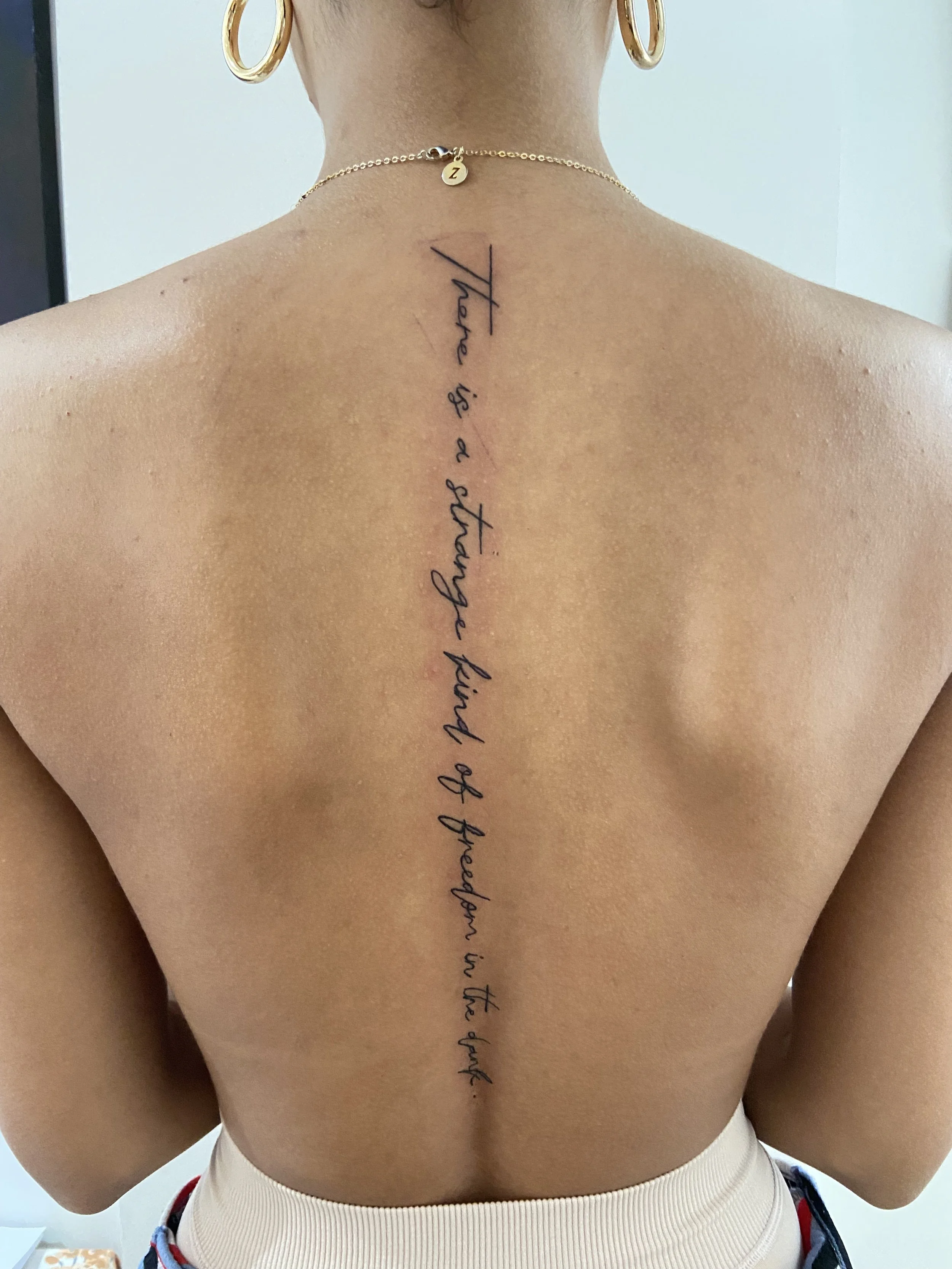 Back tattoo with cursive writing says, 'A handful is a lot to breathe in the air.'