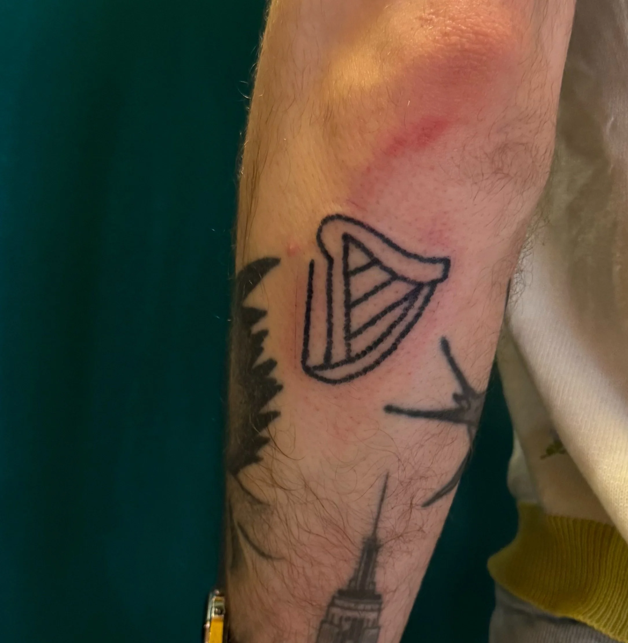 Tattoo of a sailboat and a city skyline on a person's arm