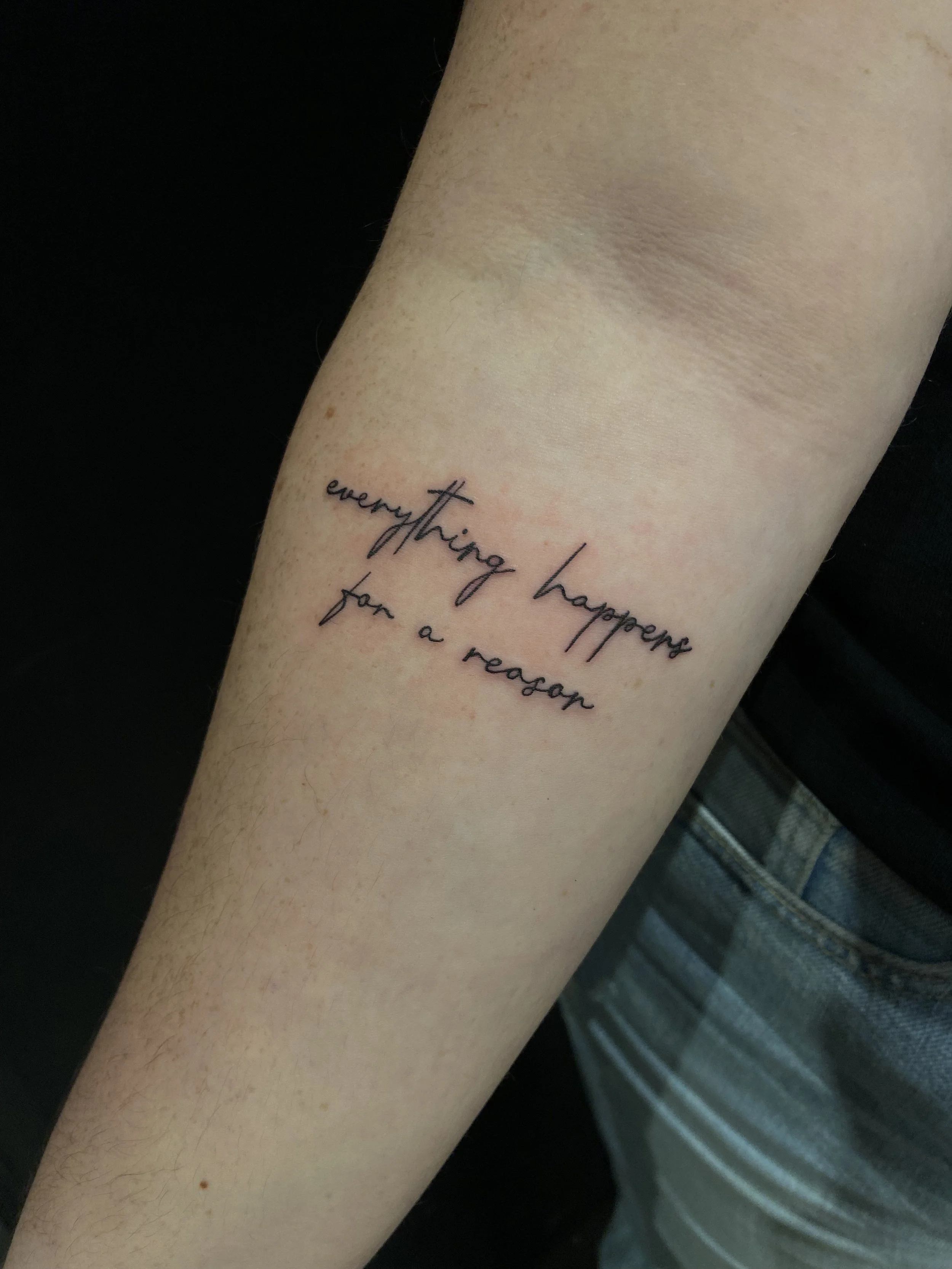 Tattoo on forearm with the phrase "everything happens for a reason" written in black cursive font.