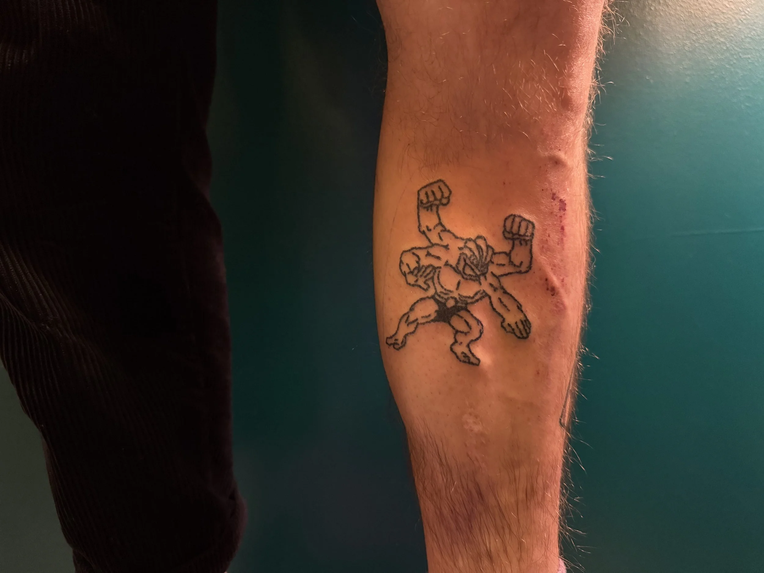 Tattoo of a muscular, roaring gorilla in a fighting stance on a person's lower leg.