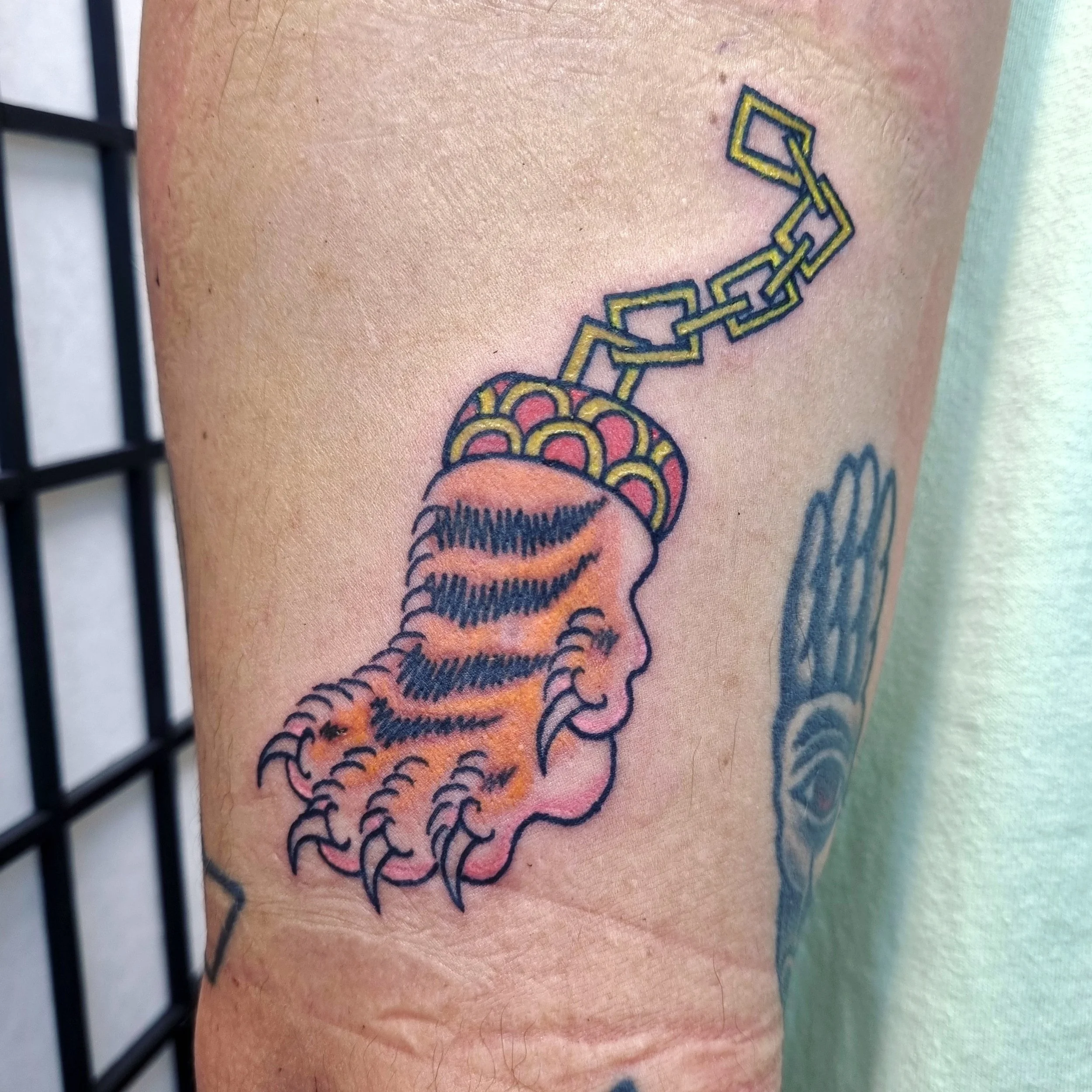 Tattoo of a human profile with tiger stripes on the face and a brain wrapped in a chain on top.
