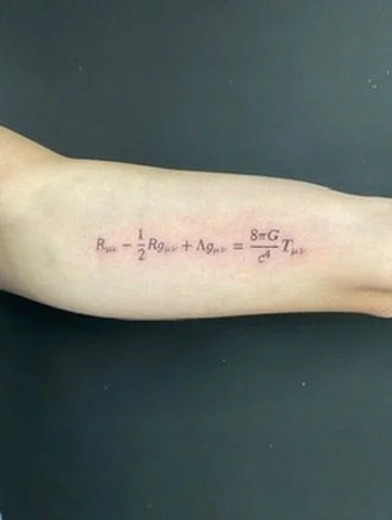 Tattoo of a physics equation on an arm, written in red ink.