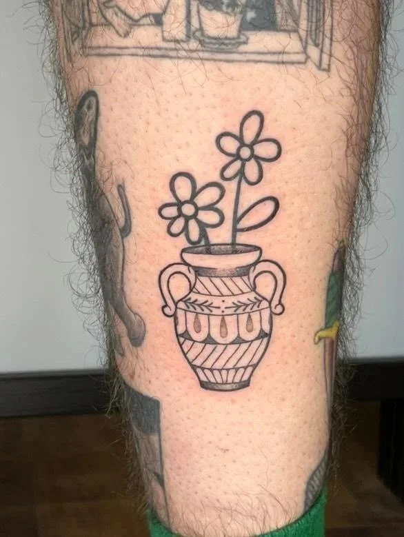 Tattoo of a fantasy goblin or elf with gray hair, pointing a sword, muscular upper body, dark tail with a yellow diamond, on a person's forearm.