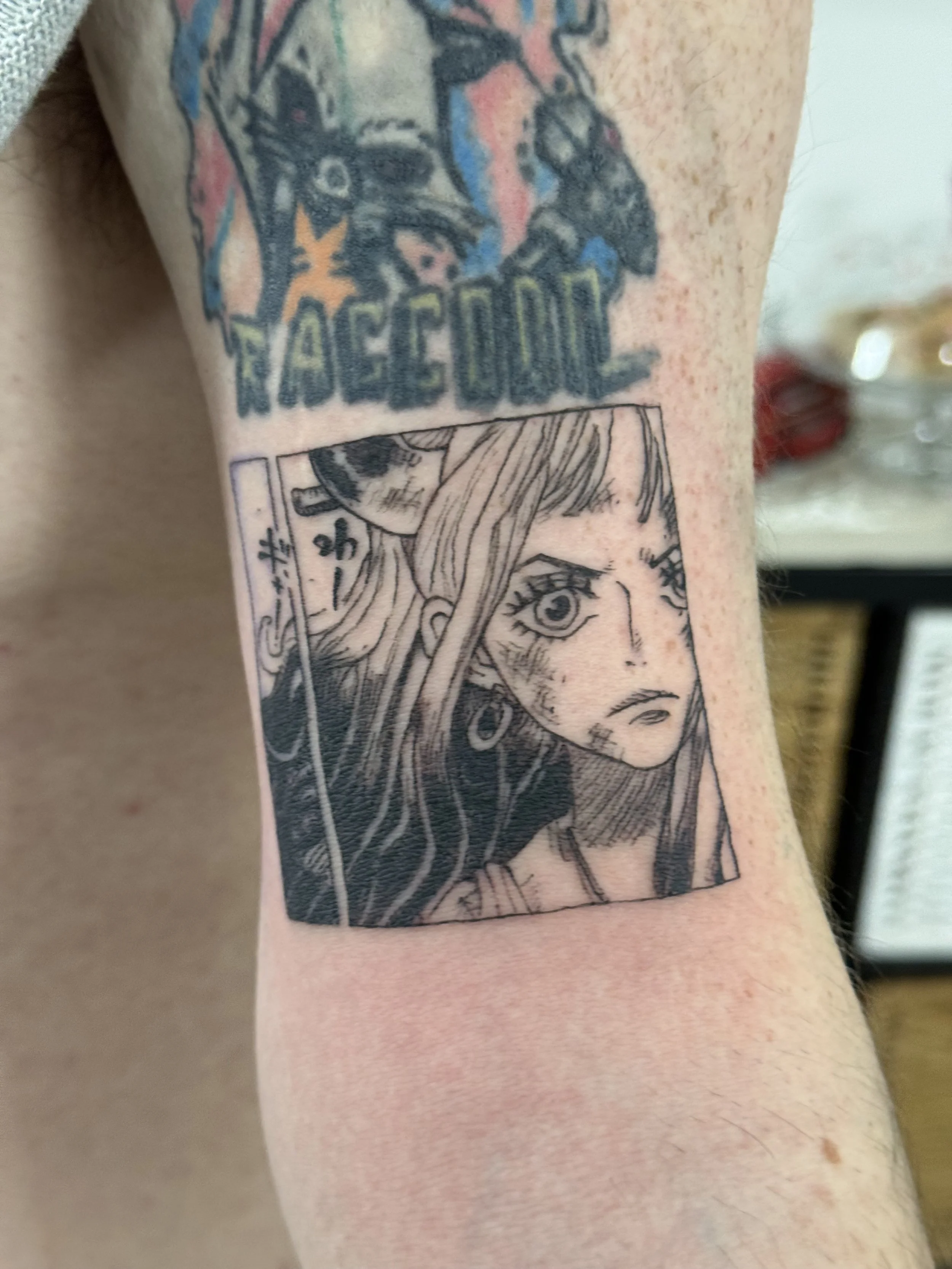 Tattoo of a manga-style girl with long hair and large expressive eyes, with Japanese text next to her.