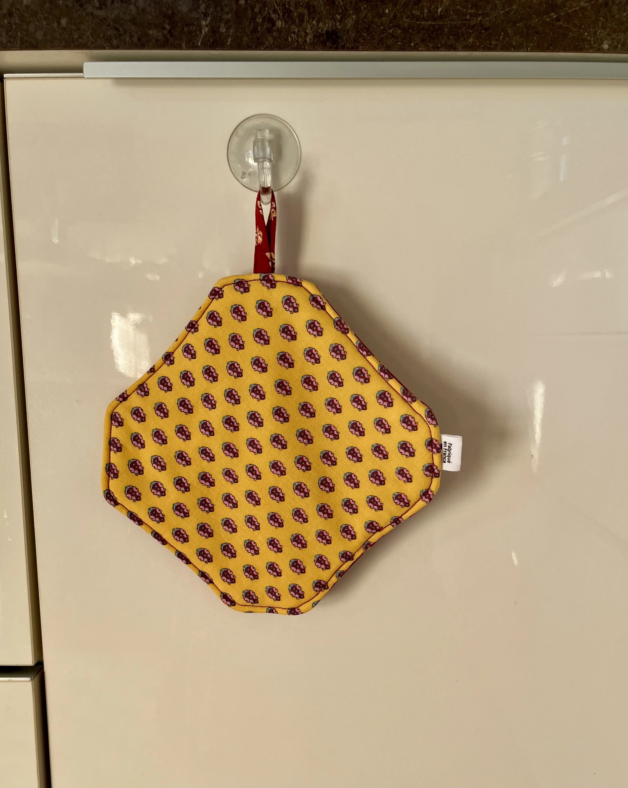 Cuisiner avec un accessoire qui a une histoire !  Cette manique Timaleli est confectionnée à partir de textiles revalorisés (tissu et serviette) pour accompagner les petits gestes du quotidien en cuisine.  Pratique et fabriquée à la main.