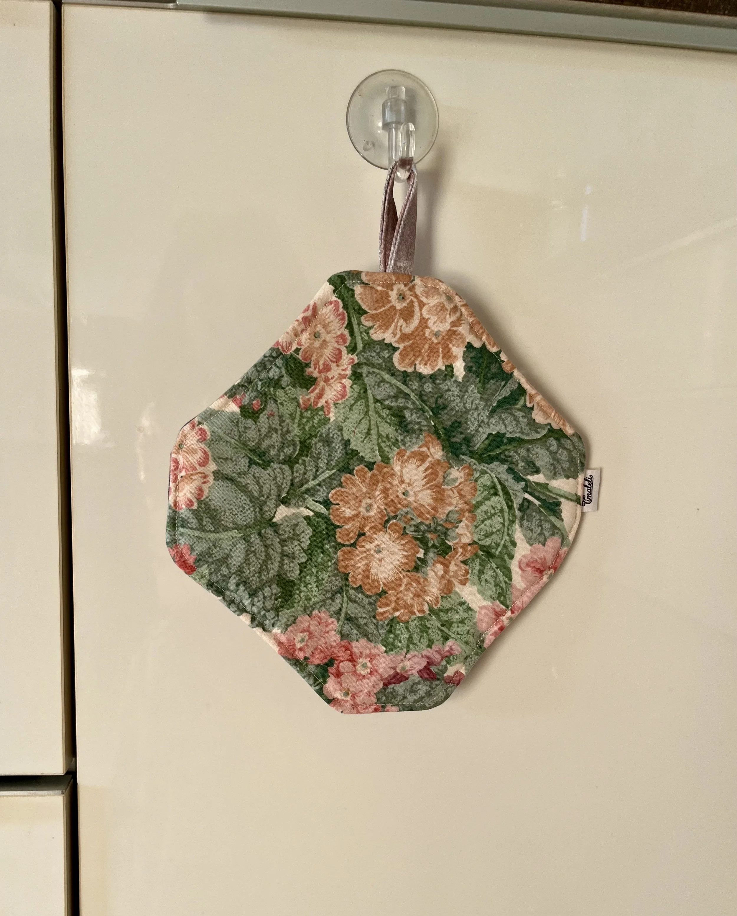 Cuisiner avec un accessoire qui a une histoire !  Cette manique Timaleli est confectionnée à partir de textiles revalorisés (tissu et serviette) pour accompagner les petits gestes du quotidien en cuisine.  Pratique et fabriquée à la main.