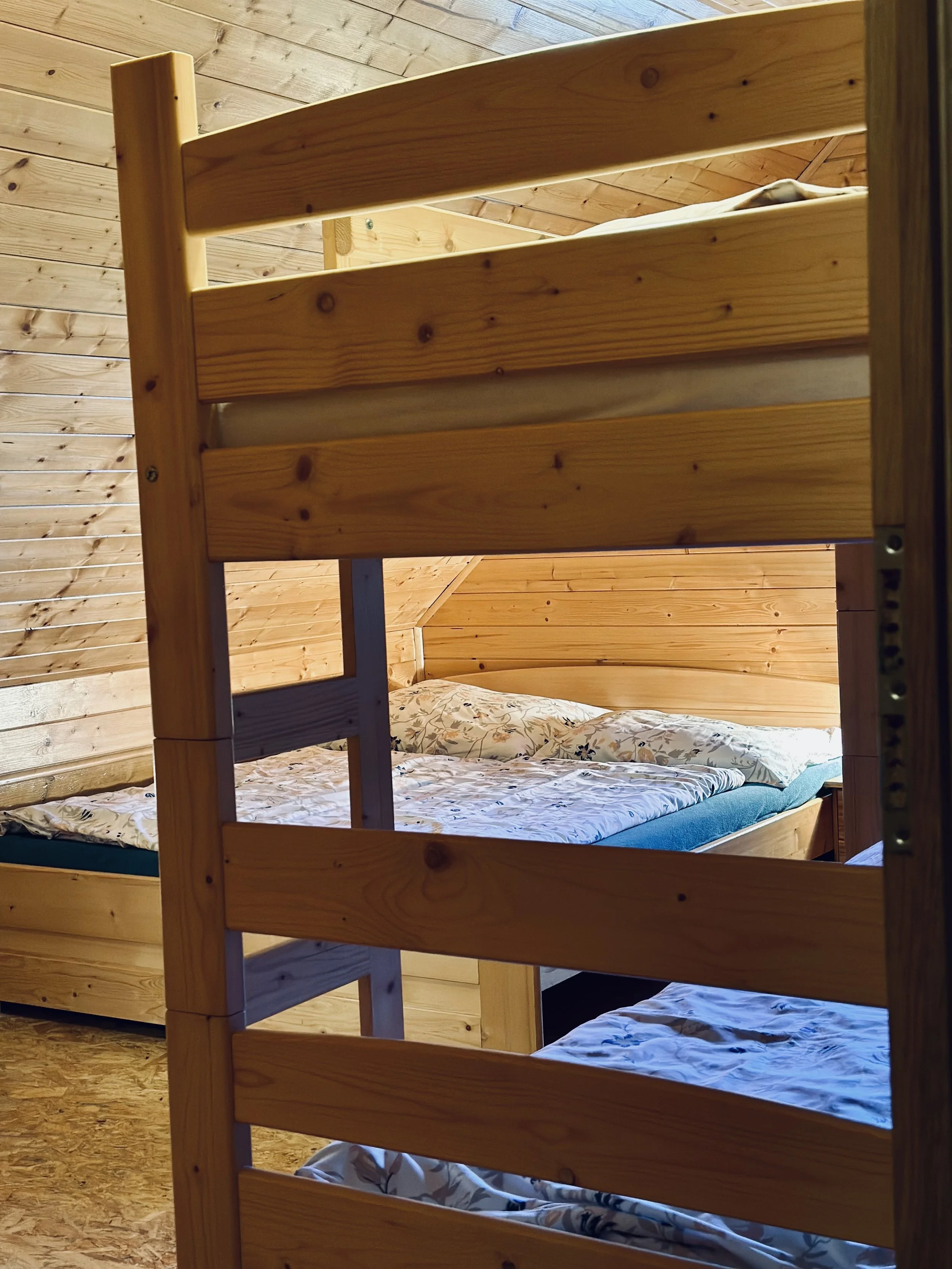 Wooden bunk beds in a cozy room with wooden walls and ceiling, with bedding and pillows.