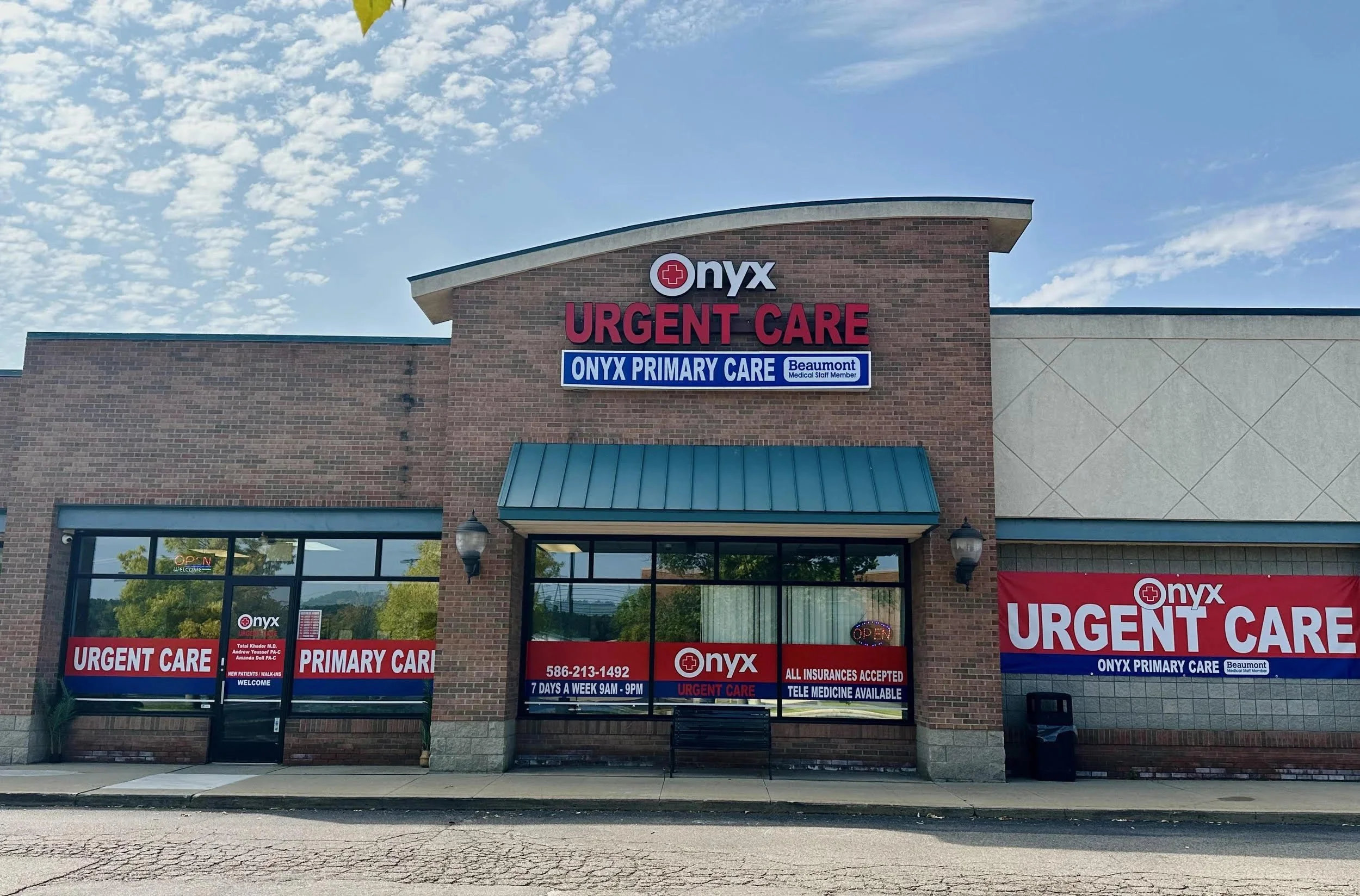 Onyx Urgent Care building with red and blue signs, brick exterior, glass windows, and a sidewalk in front, under a partly cloudy sky.