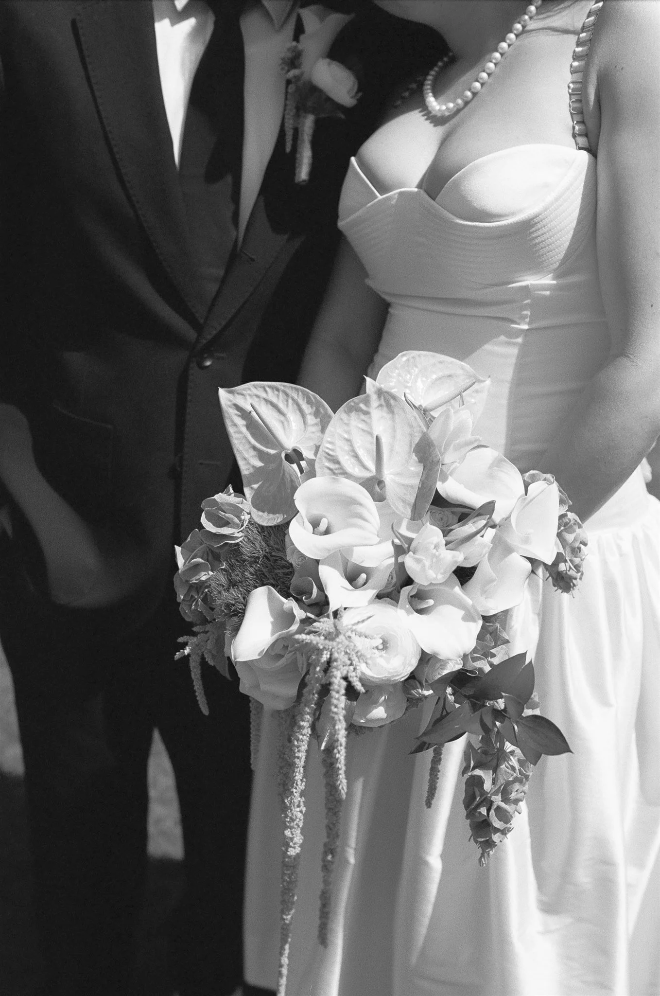 Close-up of a bride and groom holding a bouquet of flowers during a wedding ceremony, black and white photo.