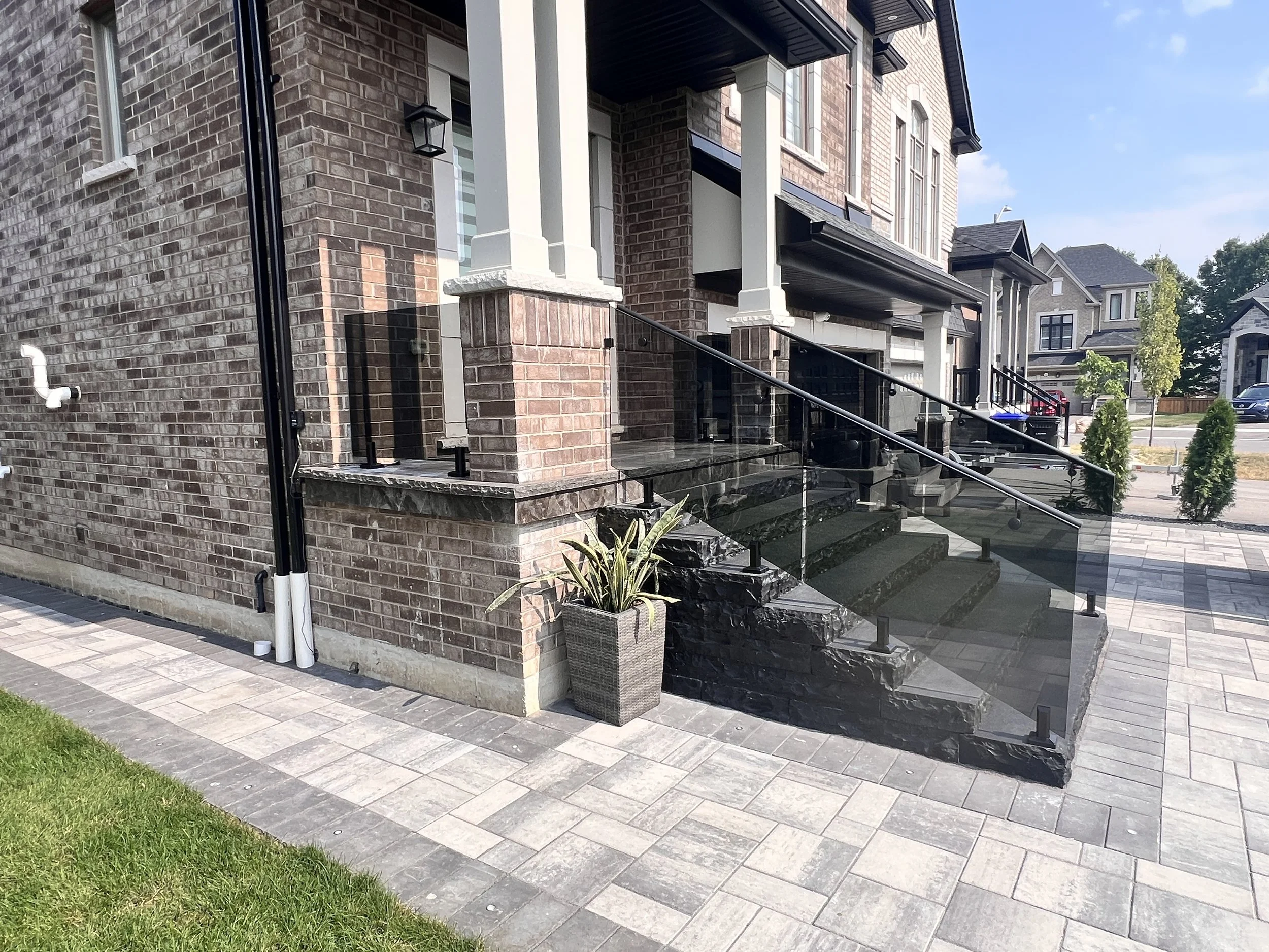 Tinted glass railing with matte black hardware on black slate steps