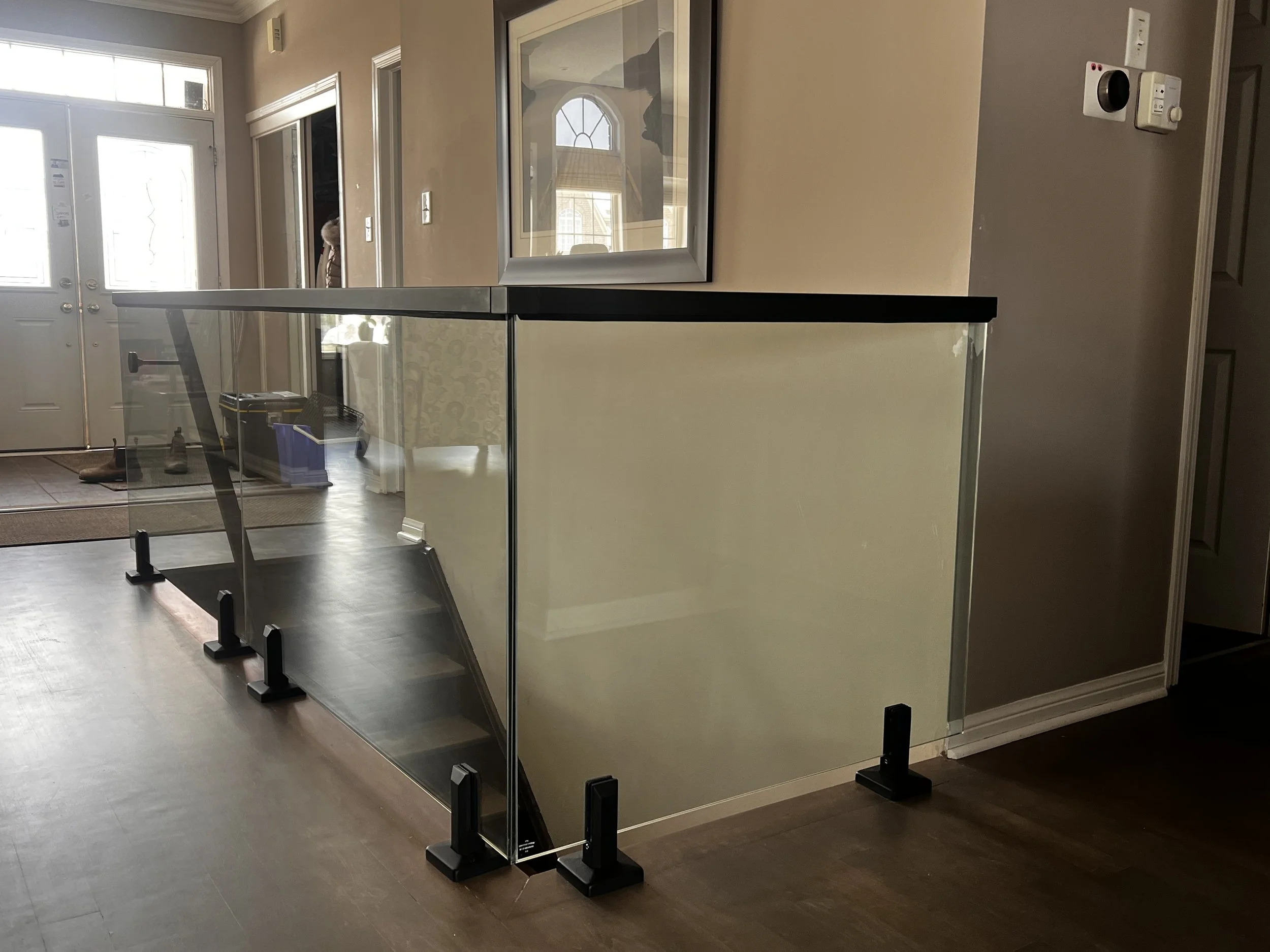 Interior view of a house with a glass safety barrier installed on a staircase landing.