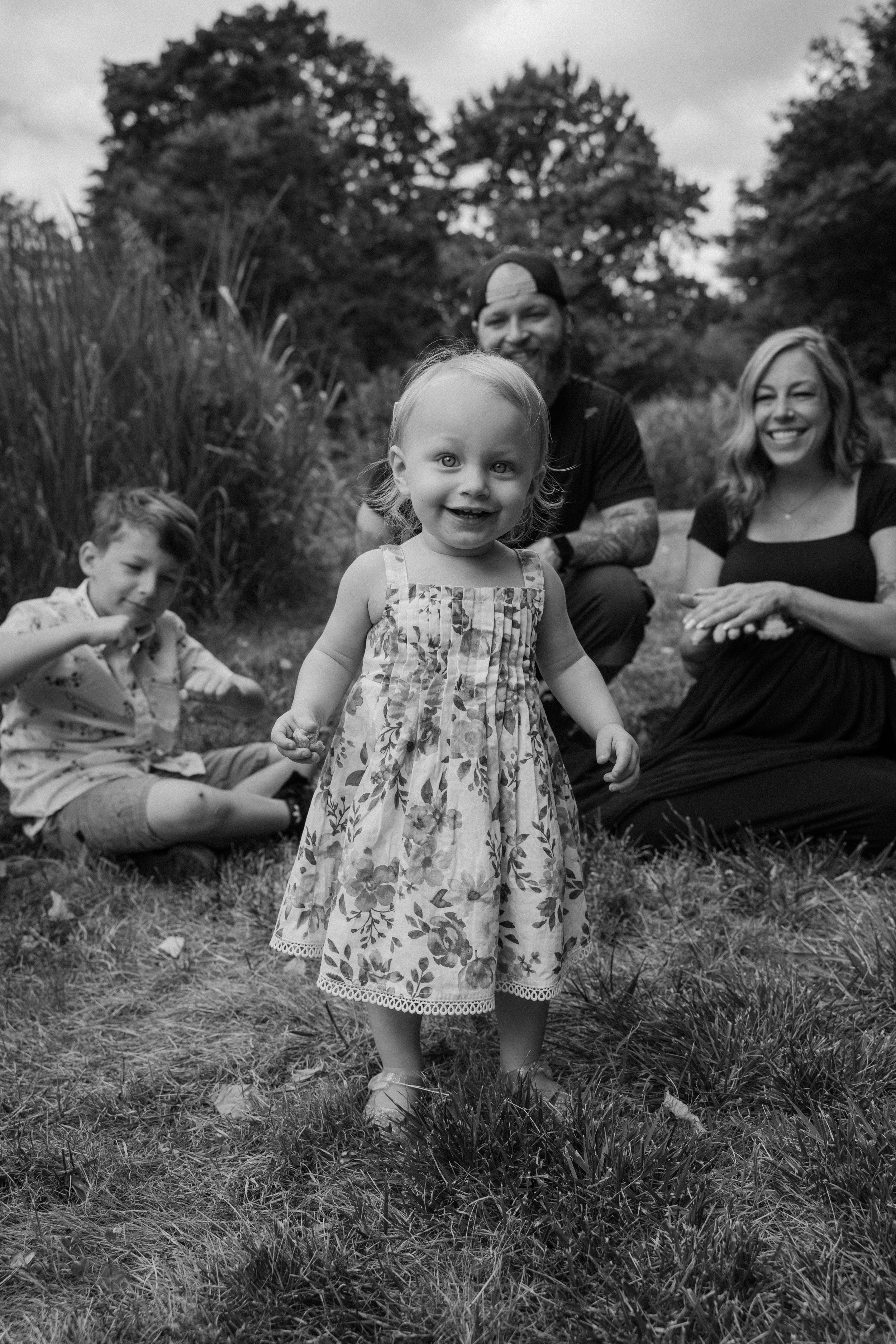 Young girl standing in front of her family photo smiling in a park in Los Angeles California