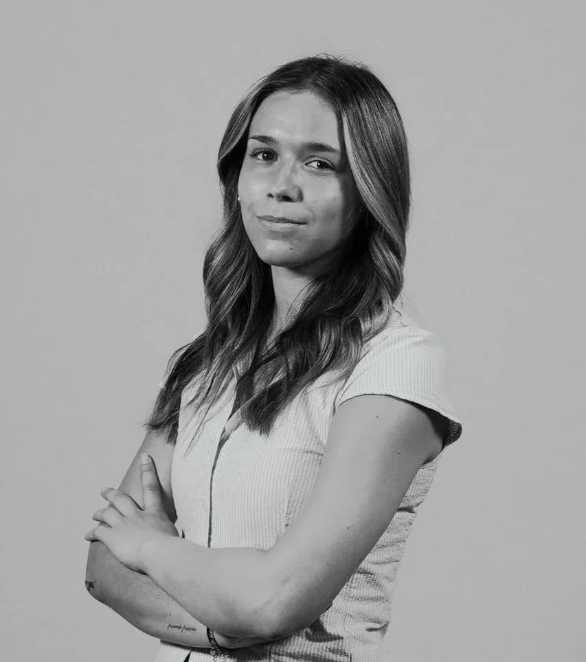 Headshot of Andie Paine standing with crossed arms while looking at the camera.