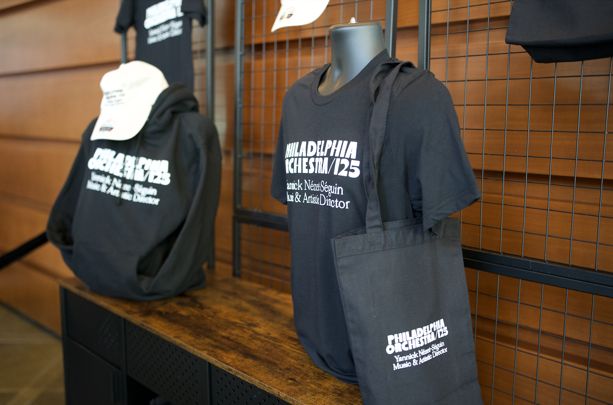 A display of Philadelphia Orchestra merchandise with a hat, hoodie, tote bag, and t-shirt with text on items: Philadelphia Orchestra / 125.