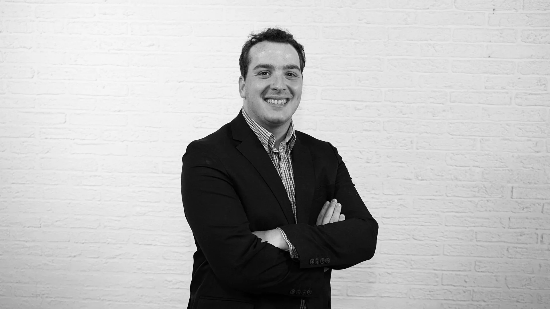 Headshot of Bryan Barlow standing slightly on an angle from the camera and smiling with his arms crossed.