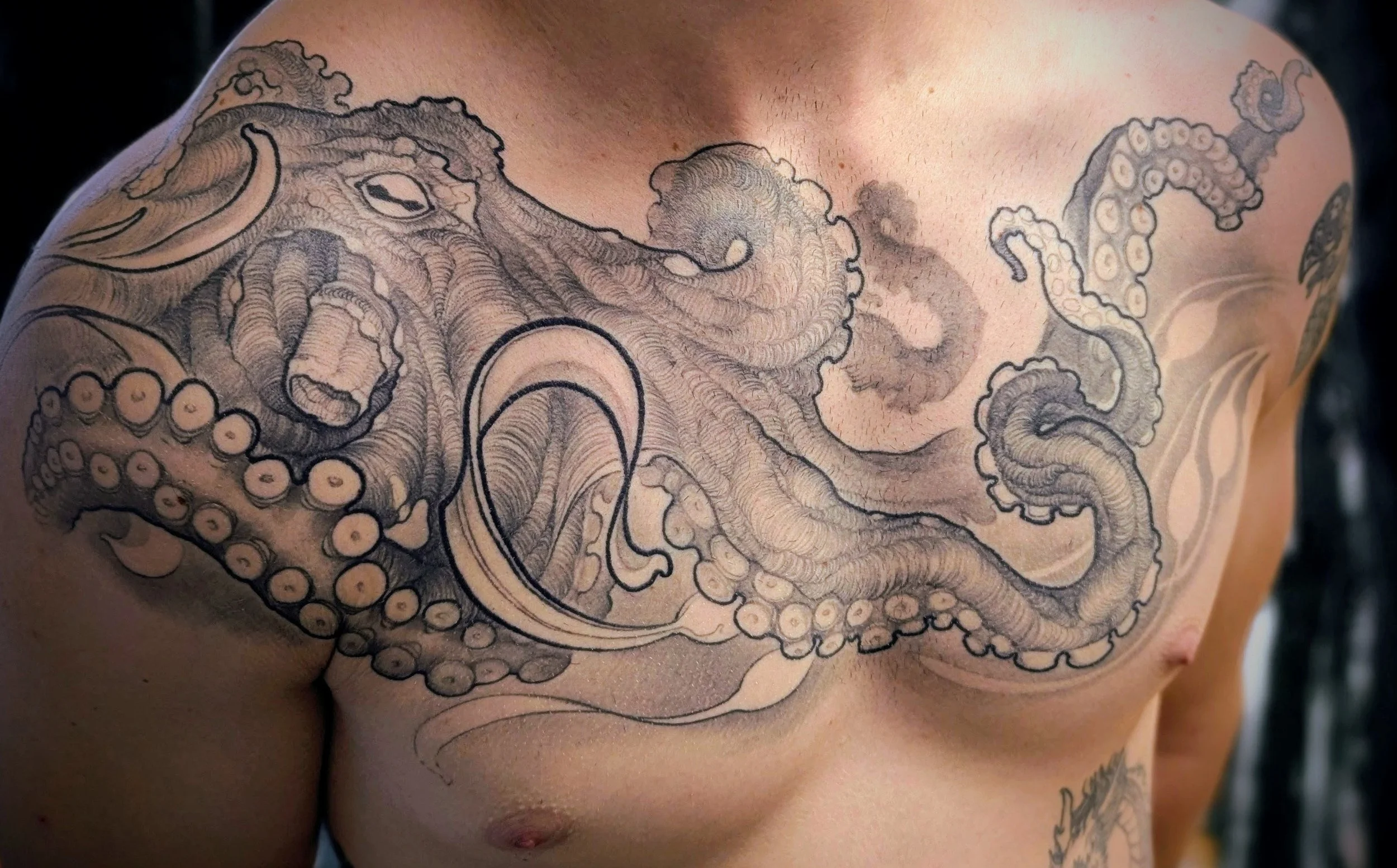 Tattoo of a detailed octopus on a person's chest and shoulder.
