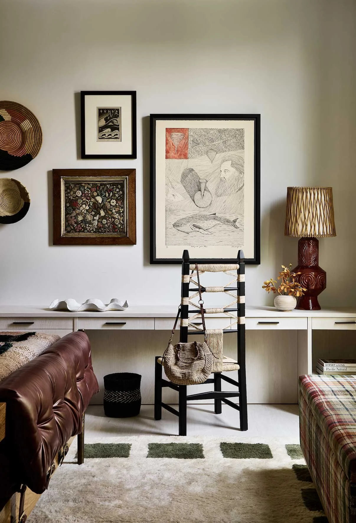 Living room with artwork, decorative baskets, a table lamp, and a brown leather couch.